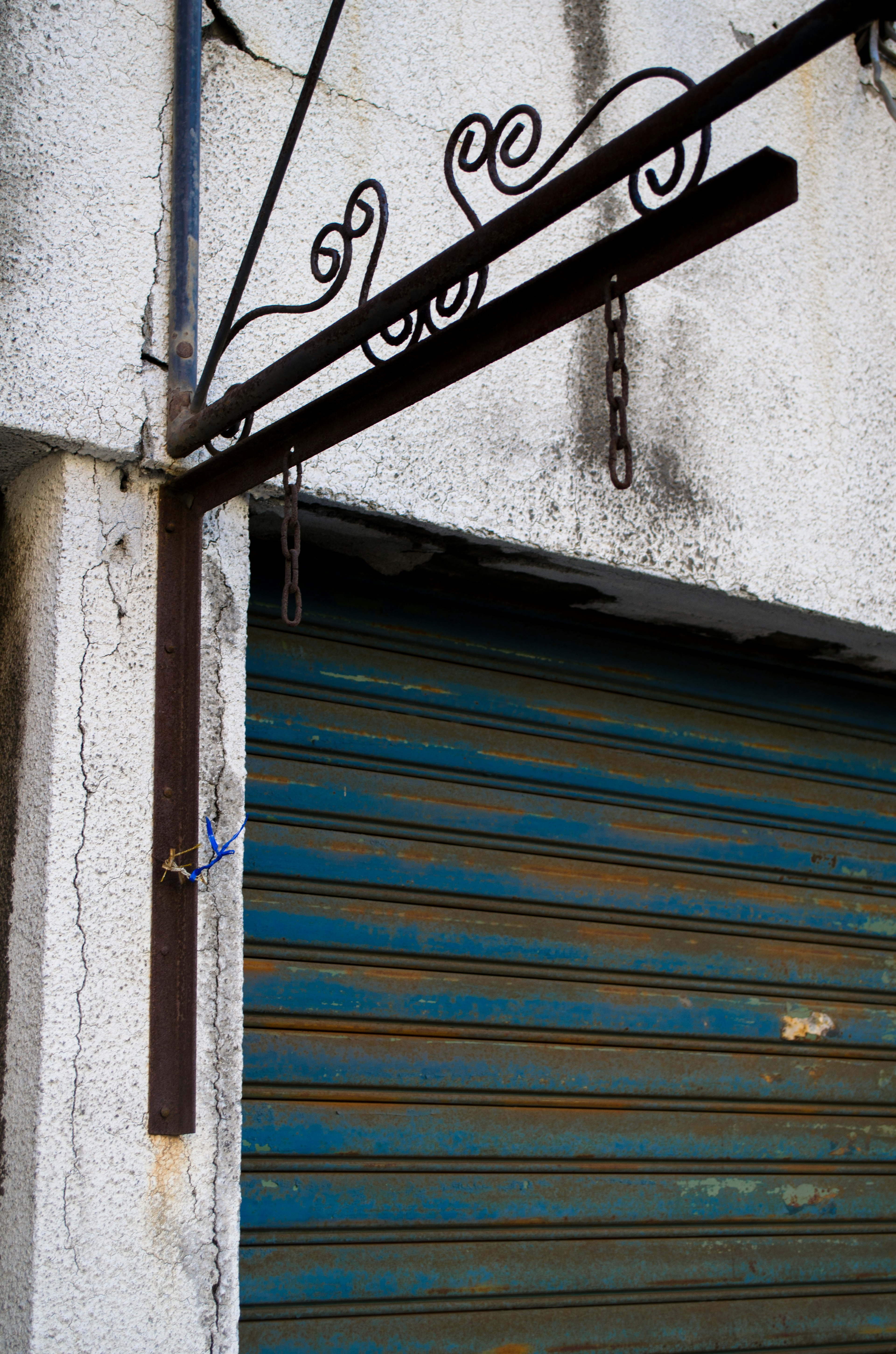 Exterior de una tienda con una persiana azul a rayas y un letrero de metal decorativo