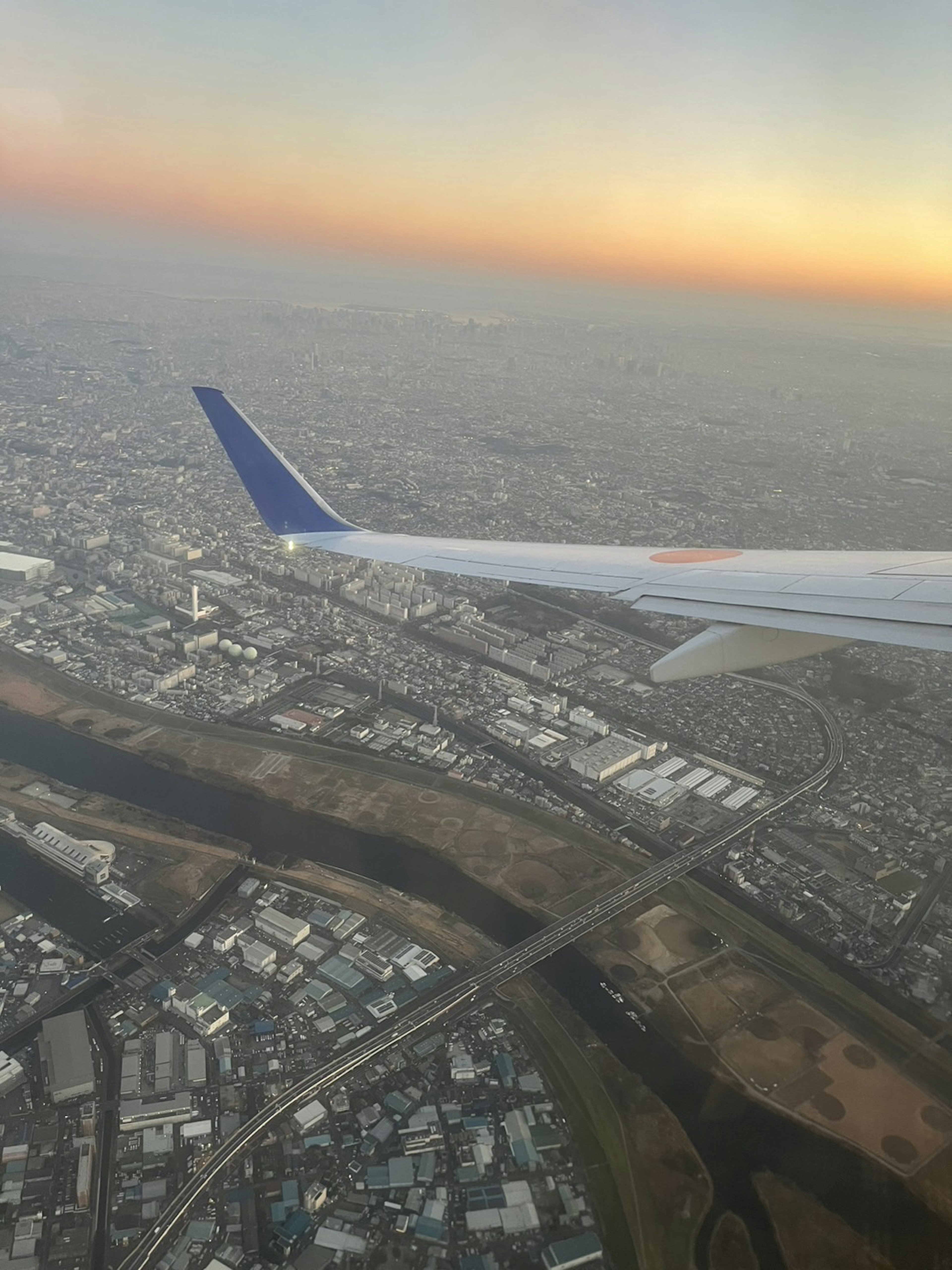 Airplane wing with cityscape under a sunset sky