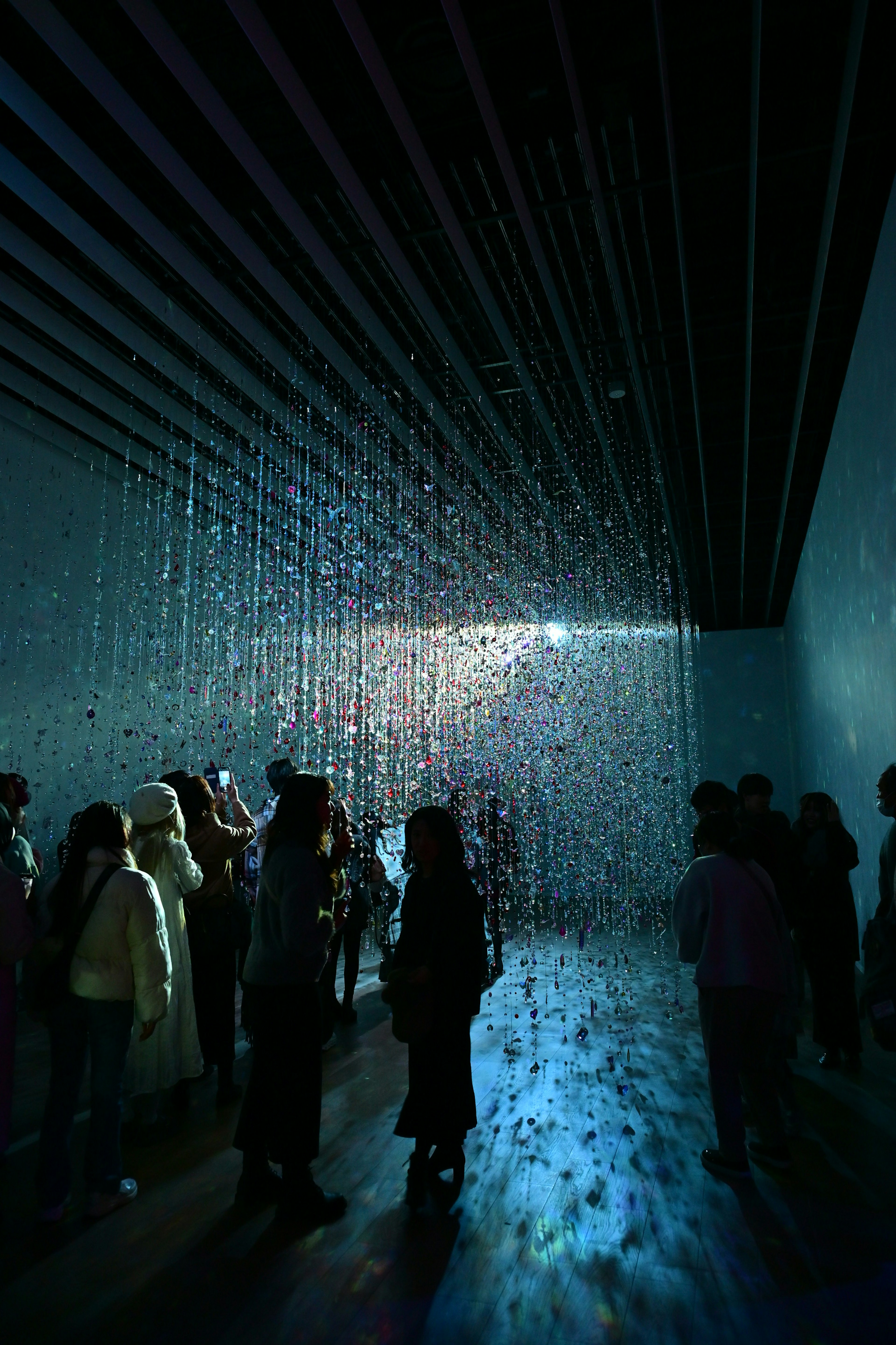 People standing under a curtain of light illuminated by blue light