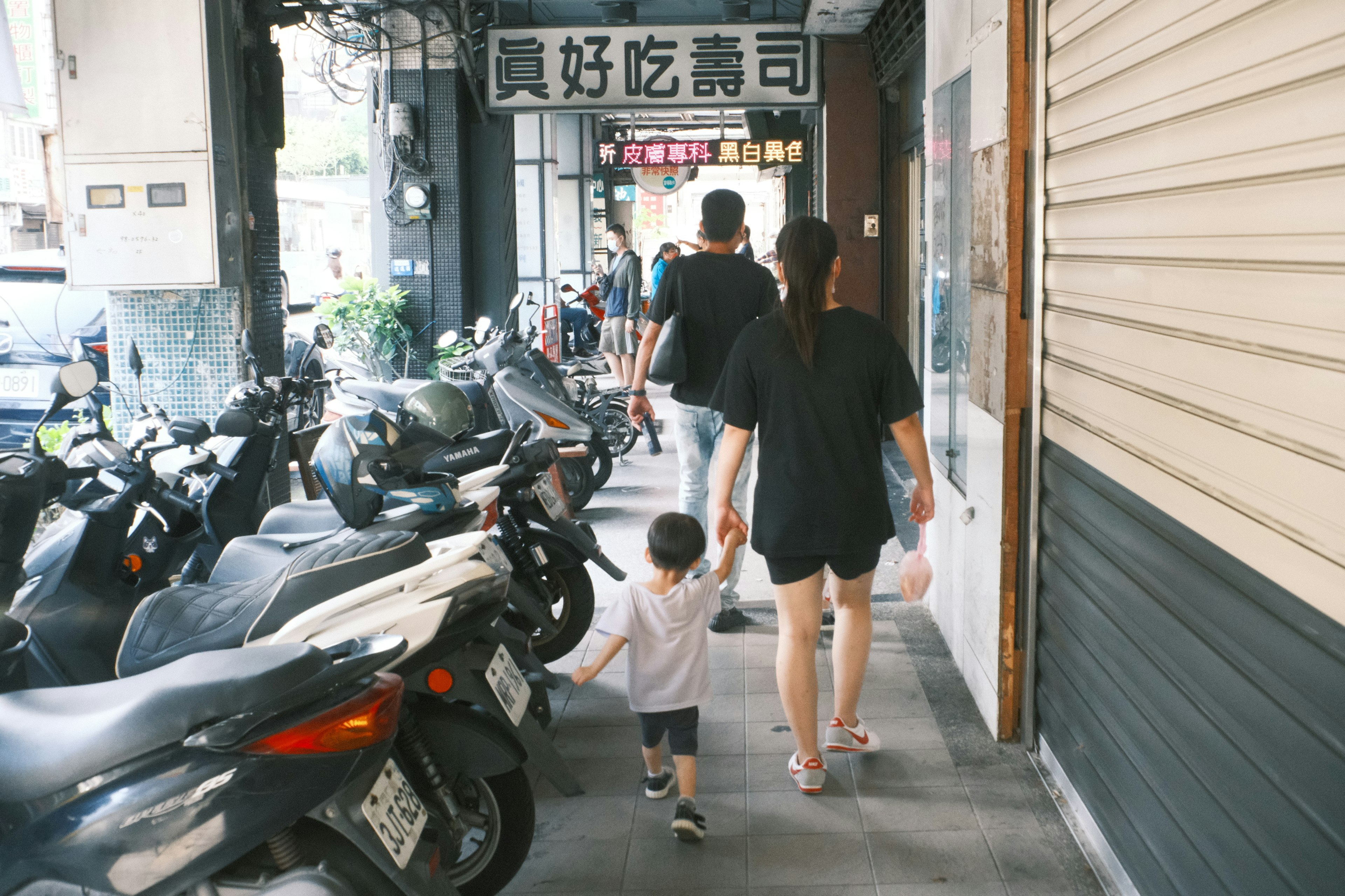 親子が手をつないで歩く街の風景 バイクが並ぶ通り