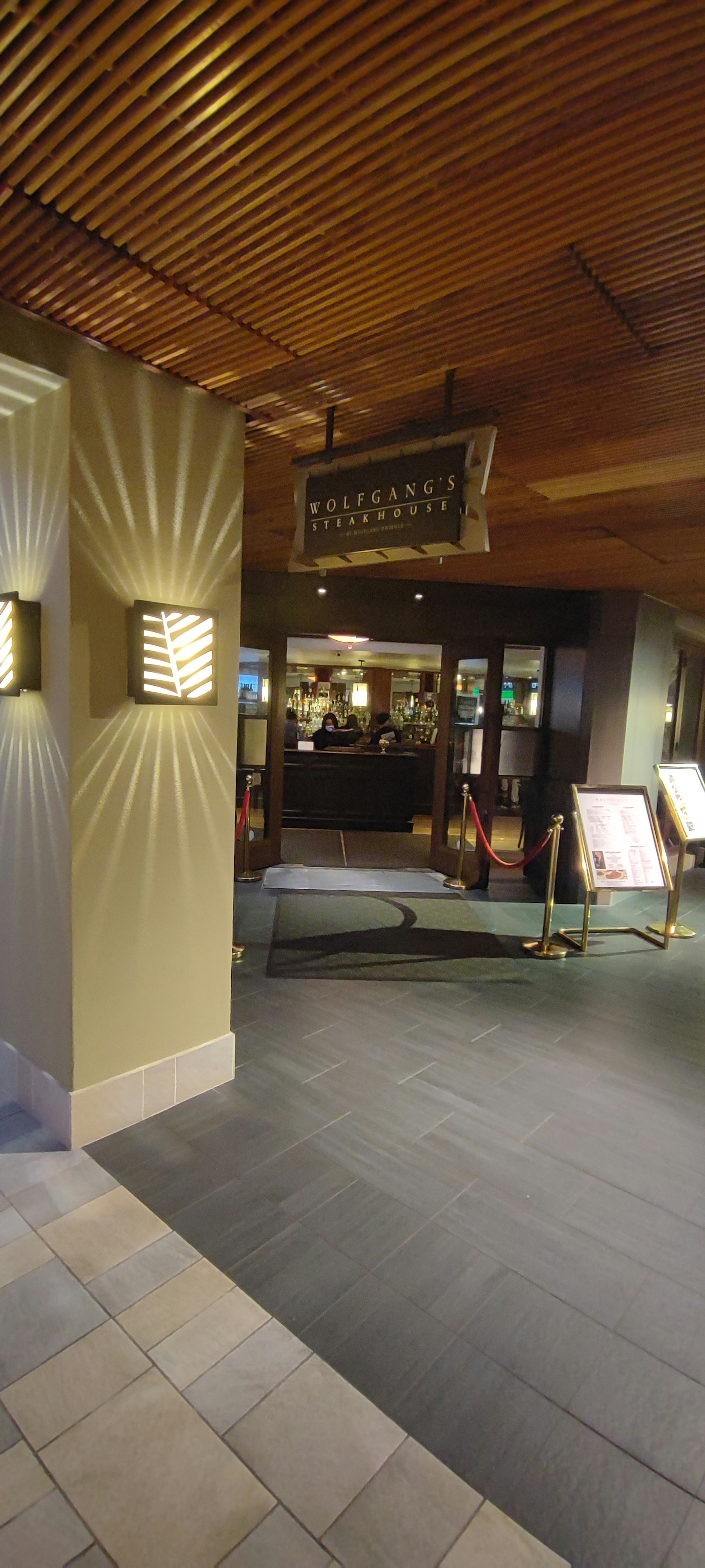 Interior view of a restaurant entrance featuring wooden ceiling and ambient lighting