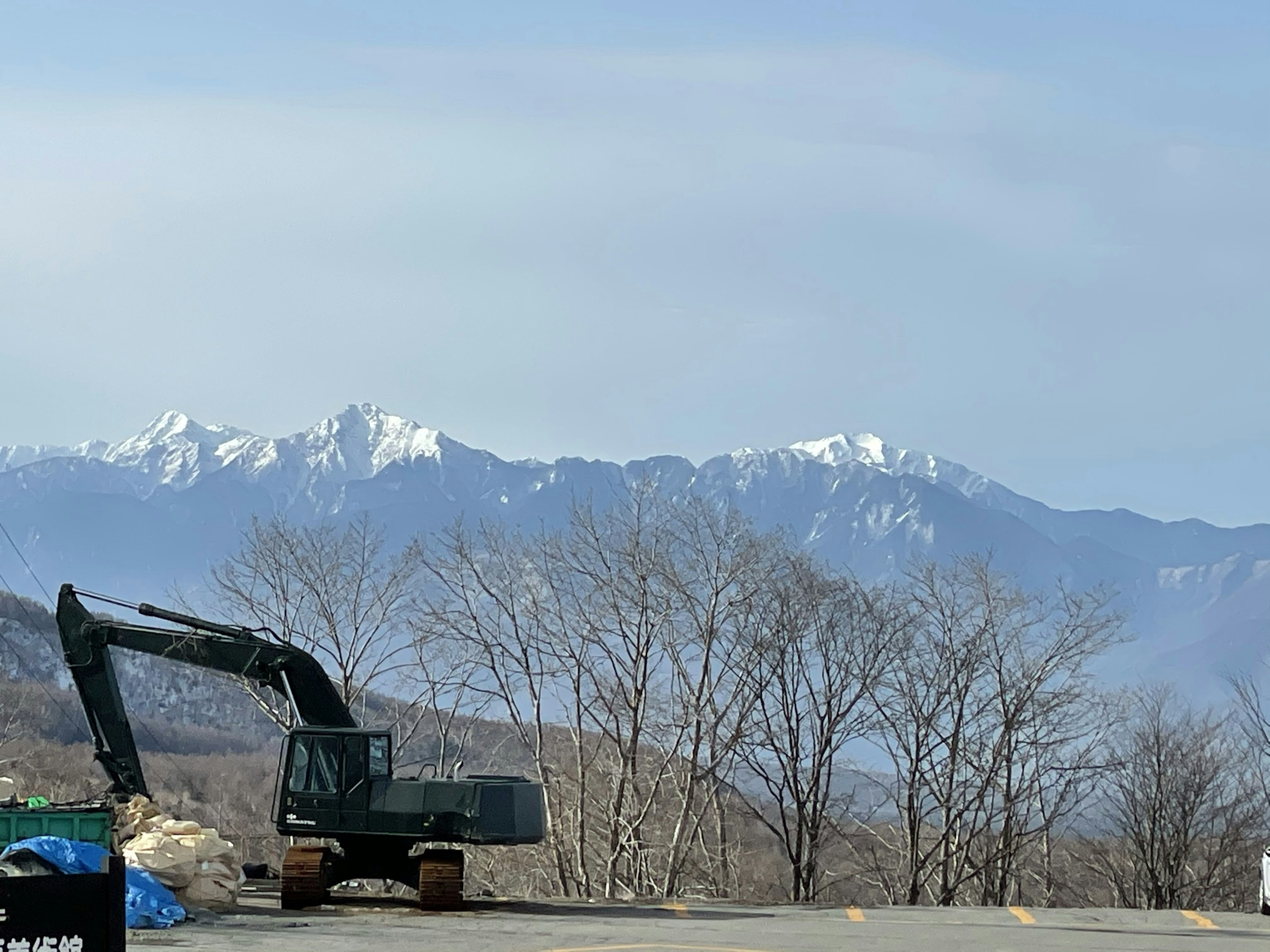 雪に覆われた山々と木々の前にある重機