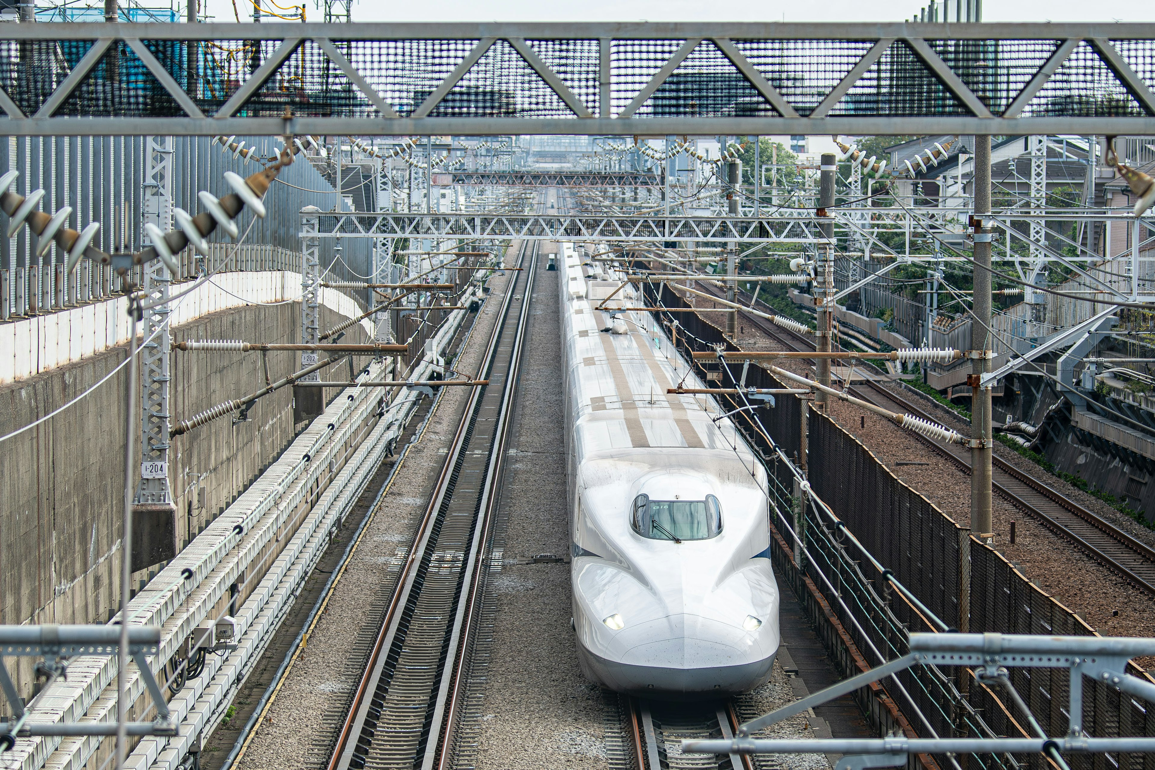 Shinkansen train approaching on tracks with surrounding railway infrastructure