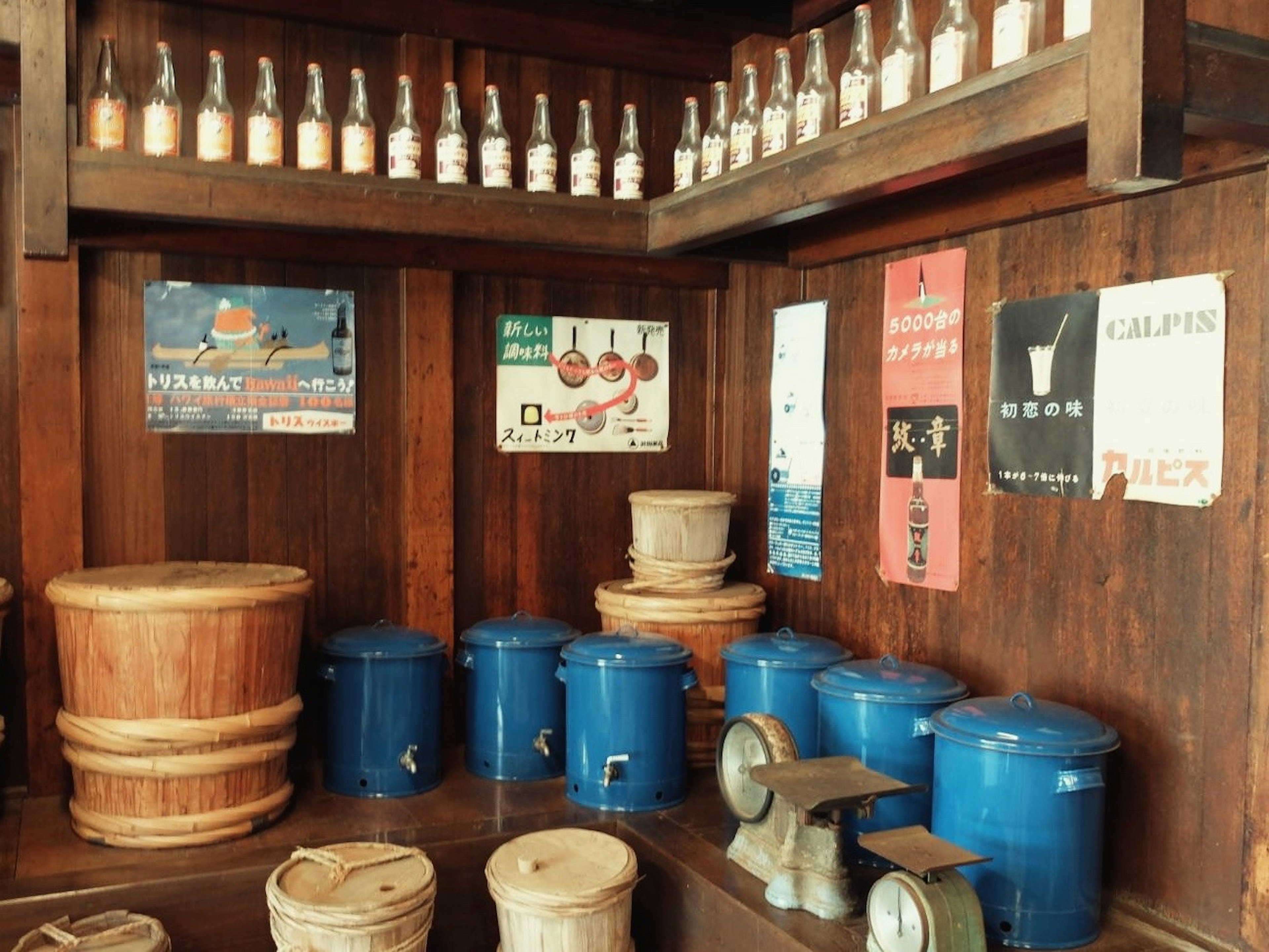 Interior toko dengan rak kayu, botol, dan poster vintage