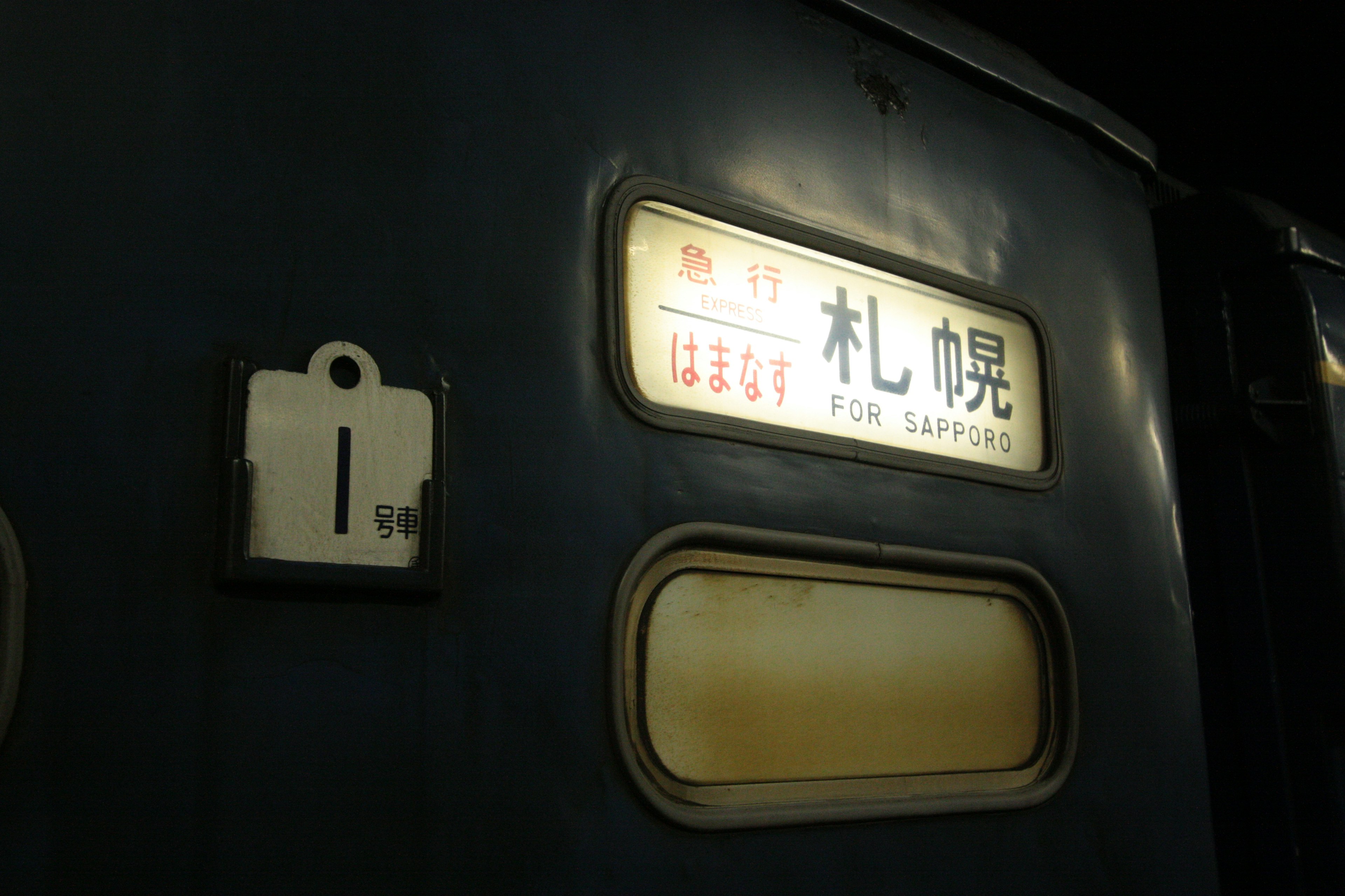 Señal en el lado de un tren que indica la estación de Sapporo por la noche