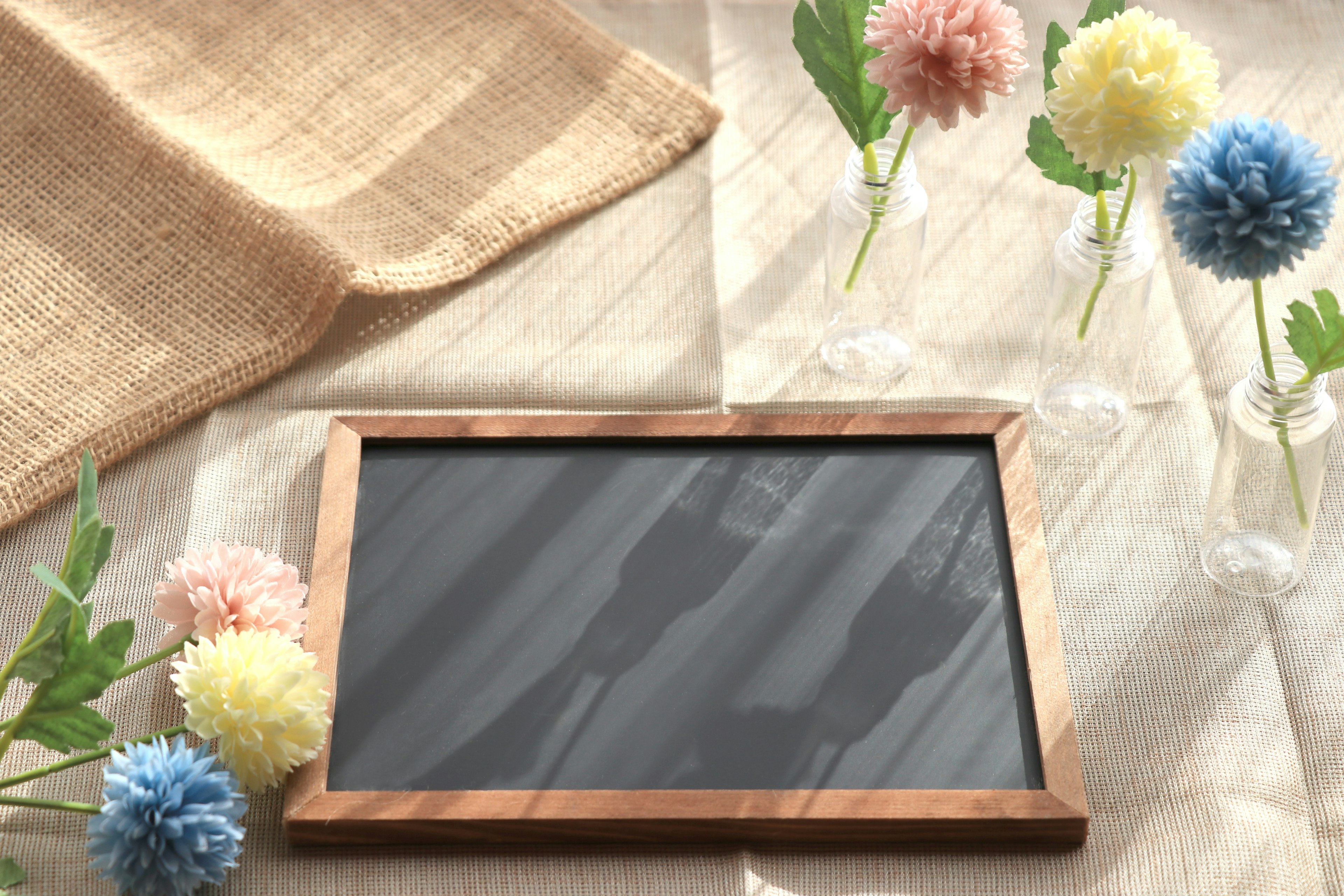 Wooden framed chalkboard surrounded by colorful pom-pom flowers on a table