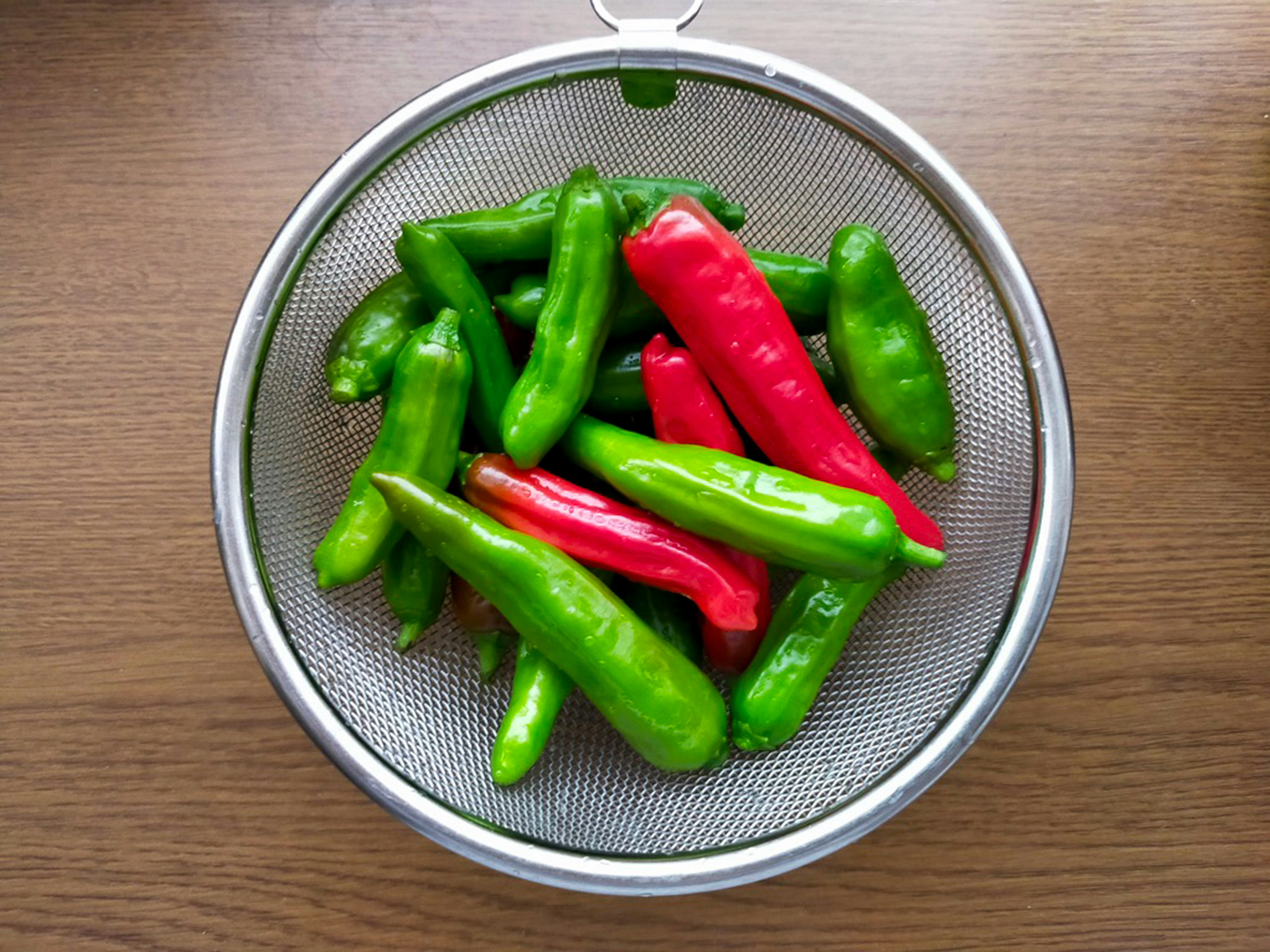 Green and red chili peppers in a colander