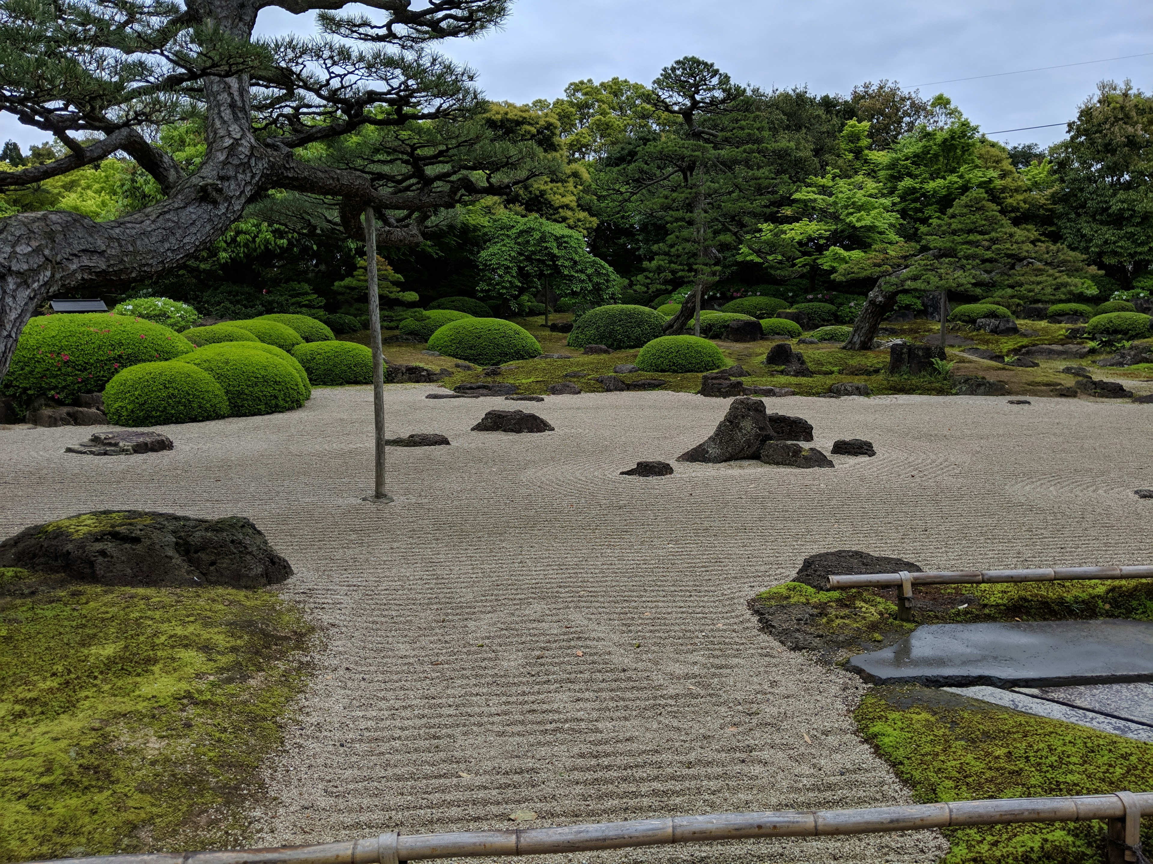 Paisaje de jardín exuberante con piedras y camino de grava cubierto de musgo