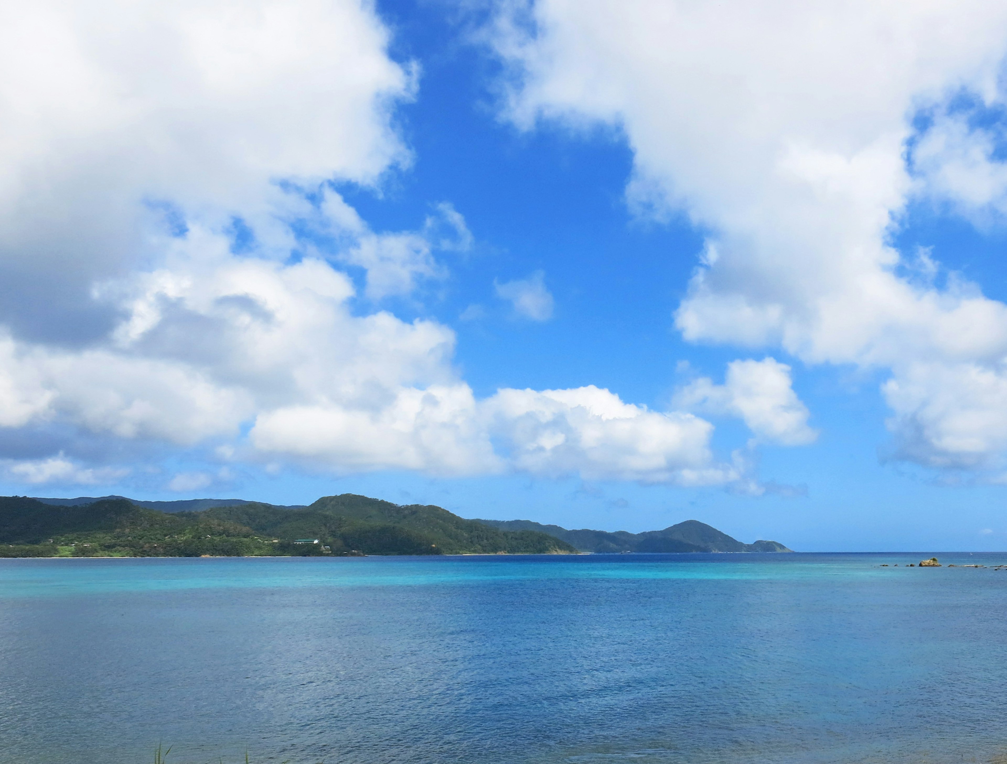 蓝色海洋和天空的风景 绿山和白云的映衬