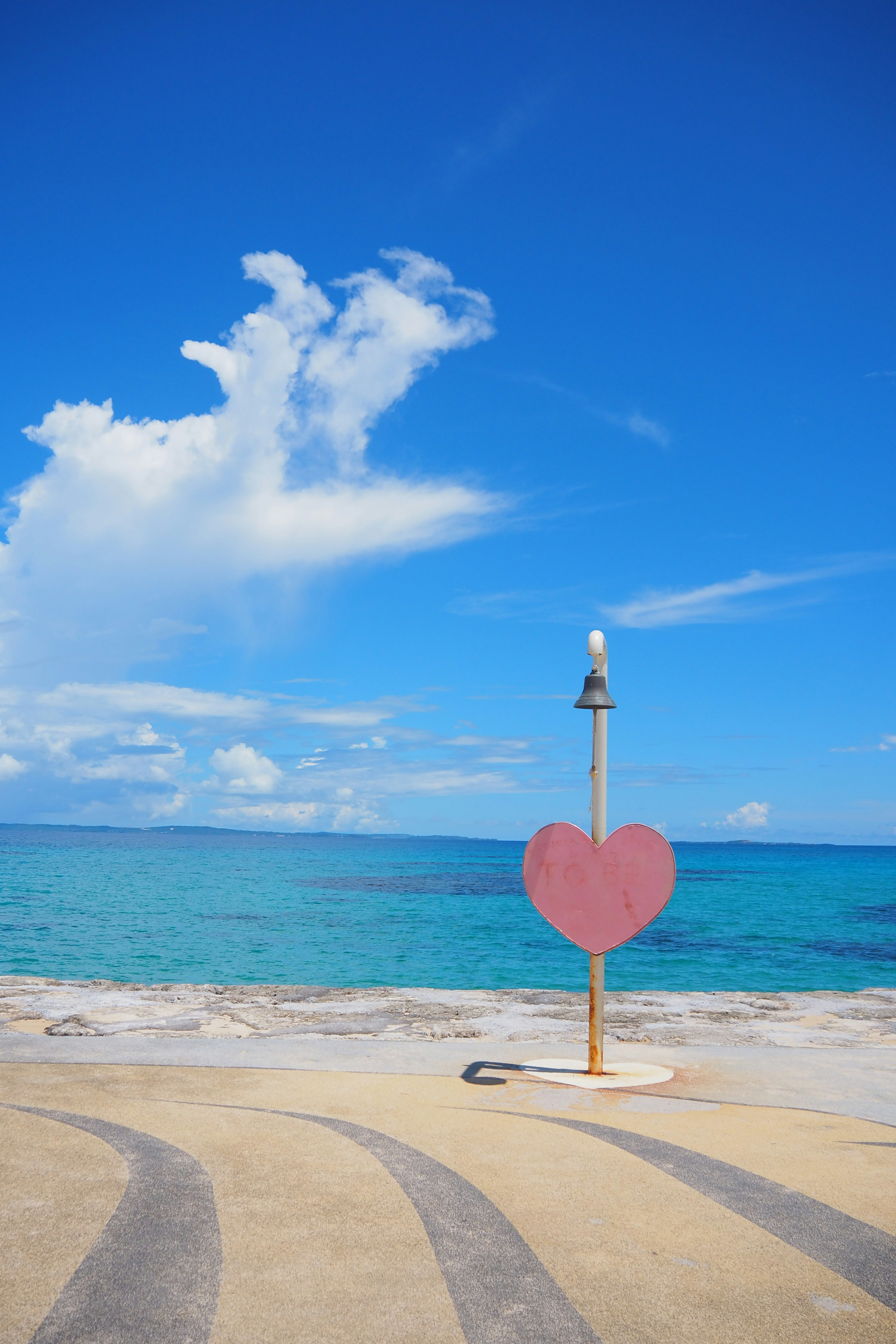 Large heart-shaped sculpture near the ocean under a blue sky