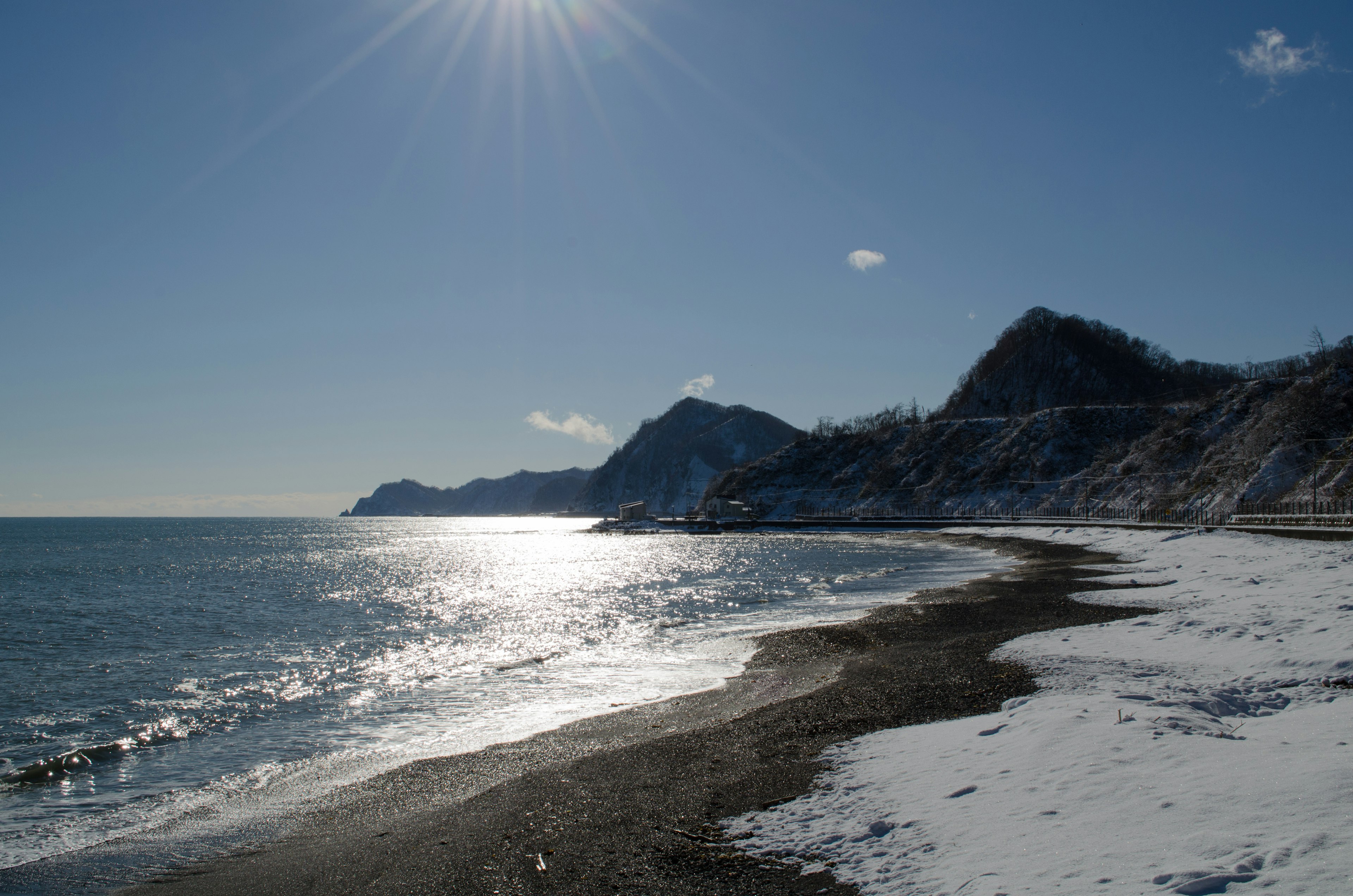 Snow-covered beach with ocean view and mountains