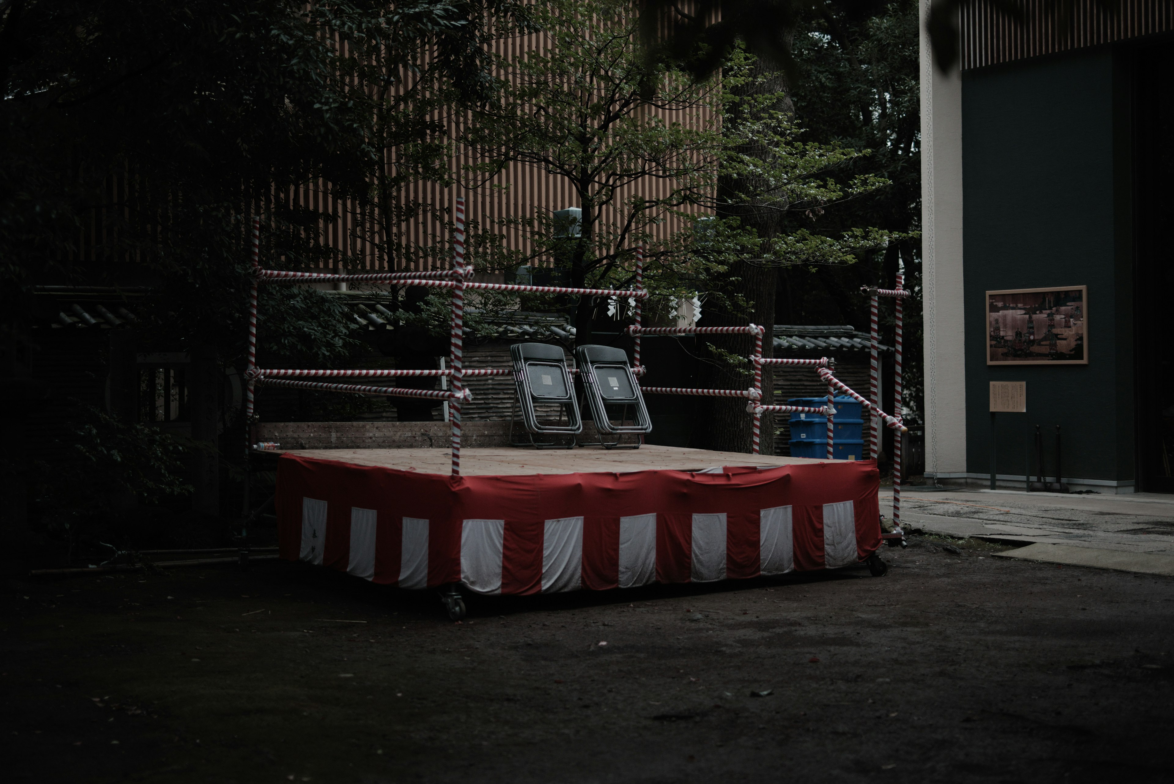 Plateforme vide sous une tente rayée rouge et blanche dans une zone sombre