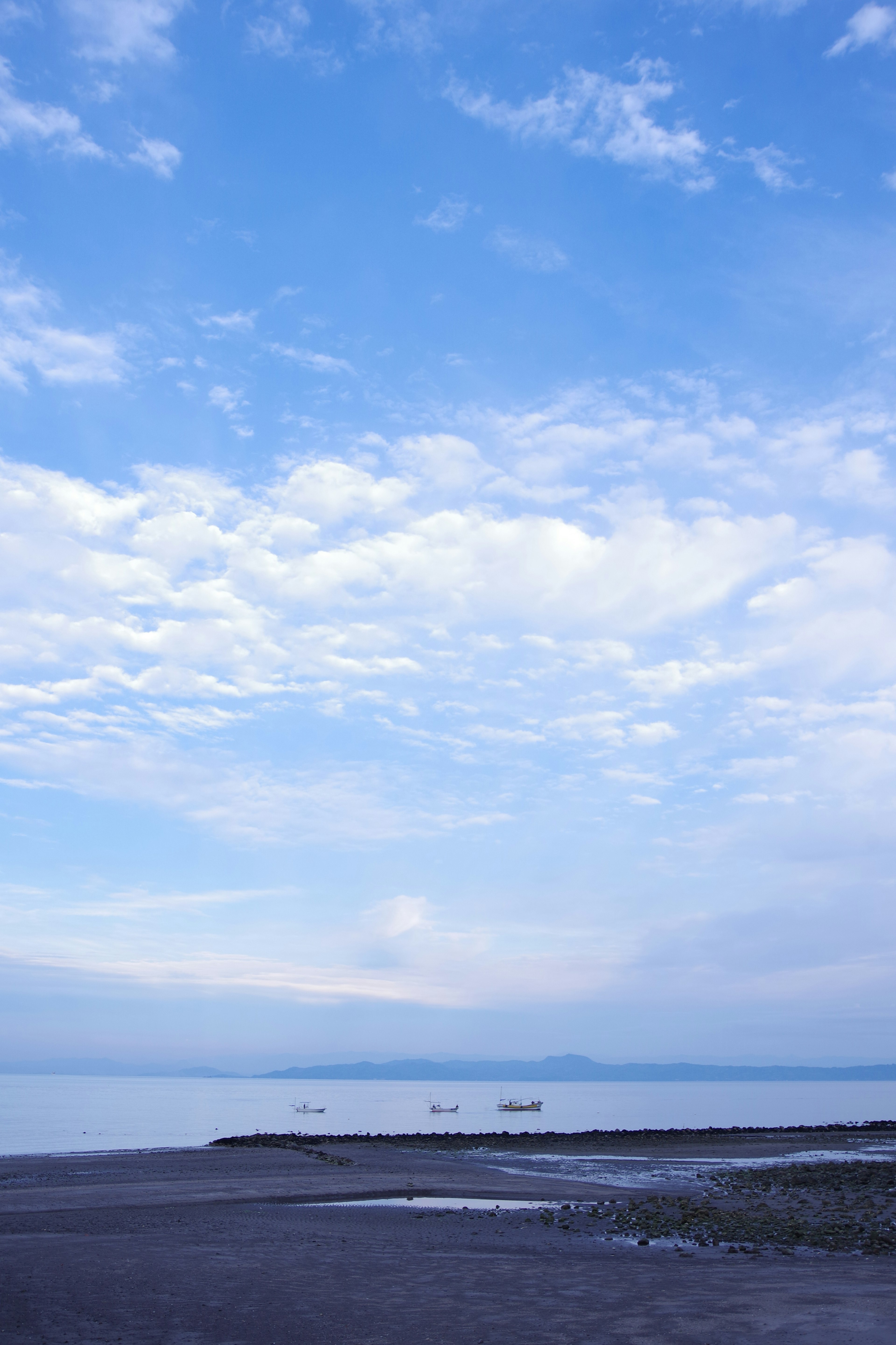 青空の下の静かな海と遠くの船