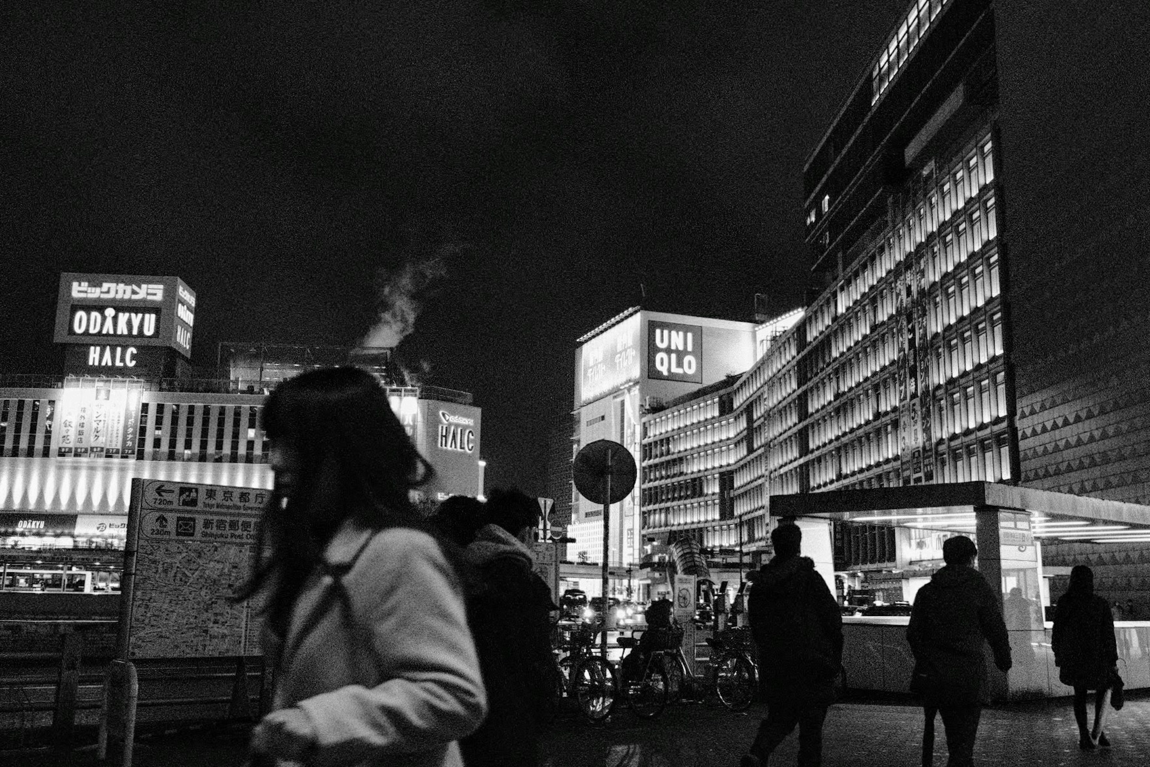 夜の街並みで通行人が行き交うモノクロの風景