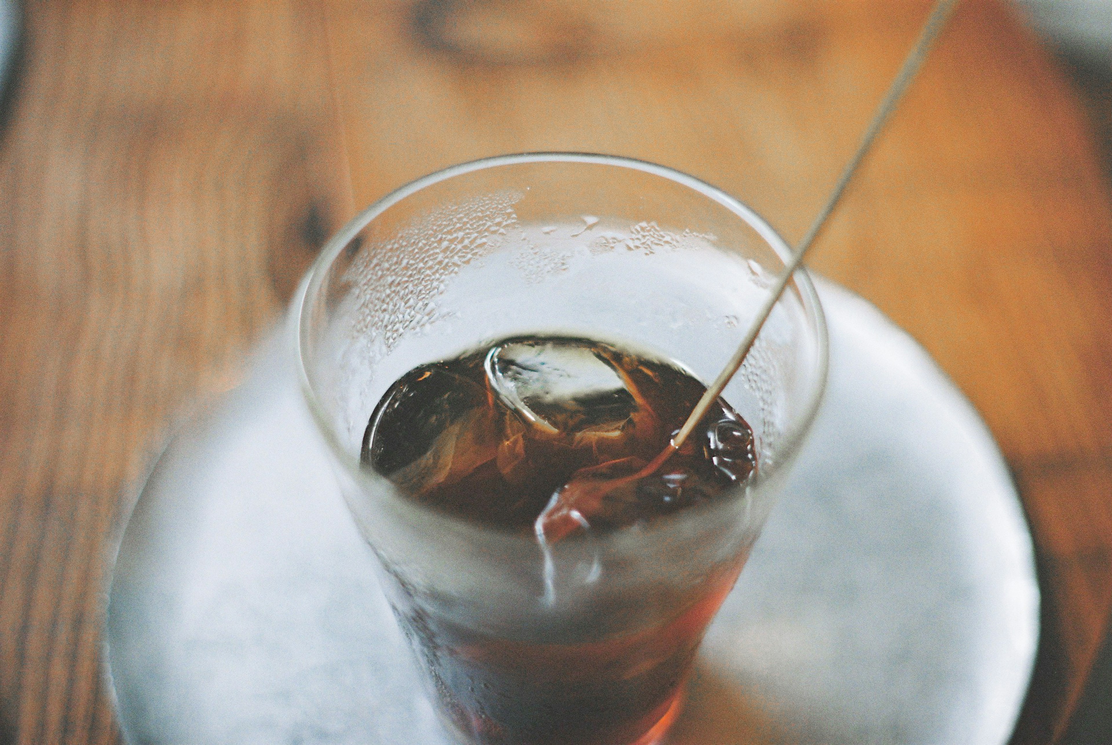 Un vaso de bebida fría con hielo sobre una mesa de madera