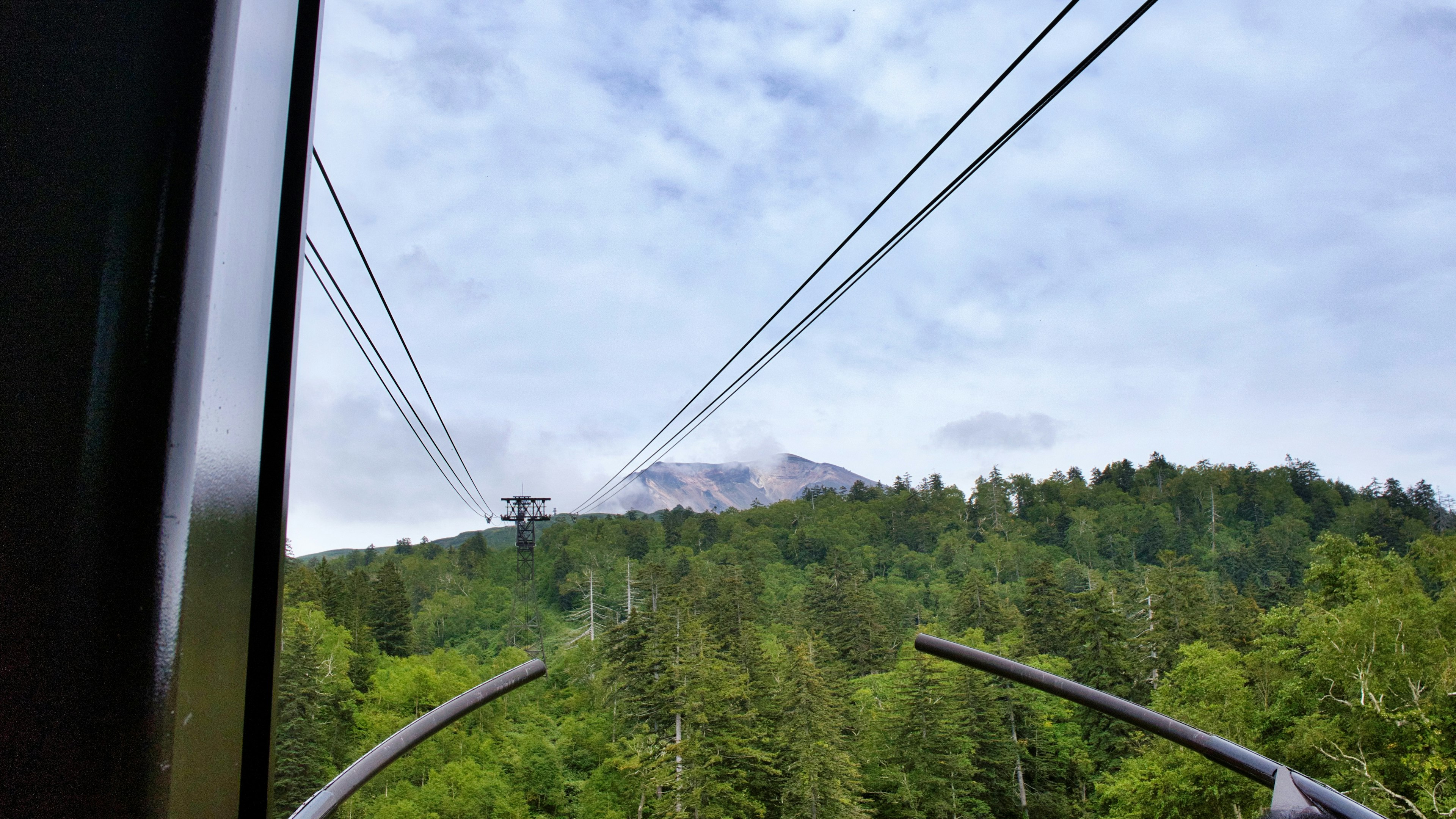 Aussicht von einer Seilbahn mit üppigen grünen Wäldern und entfernten Bergen