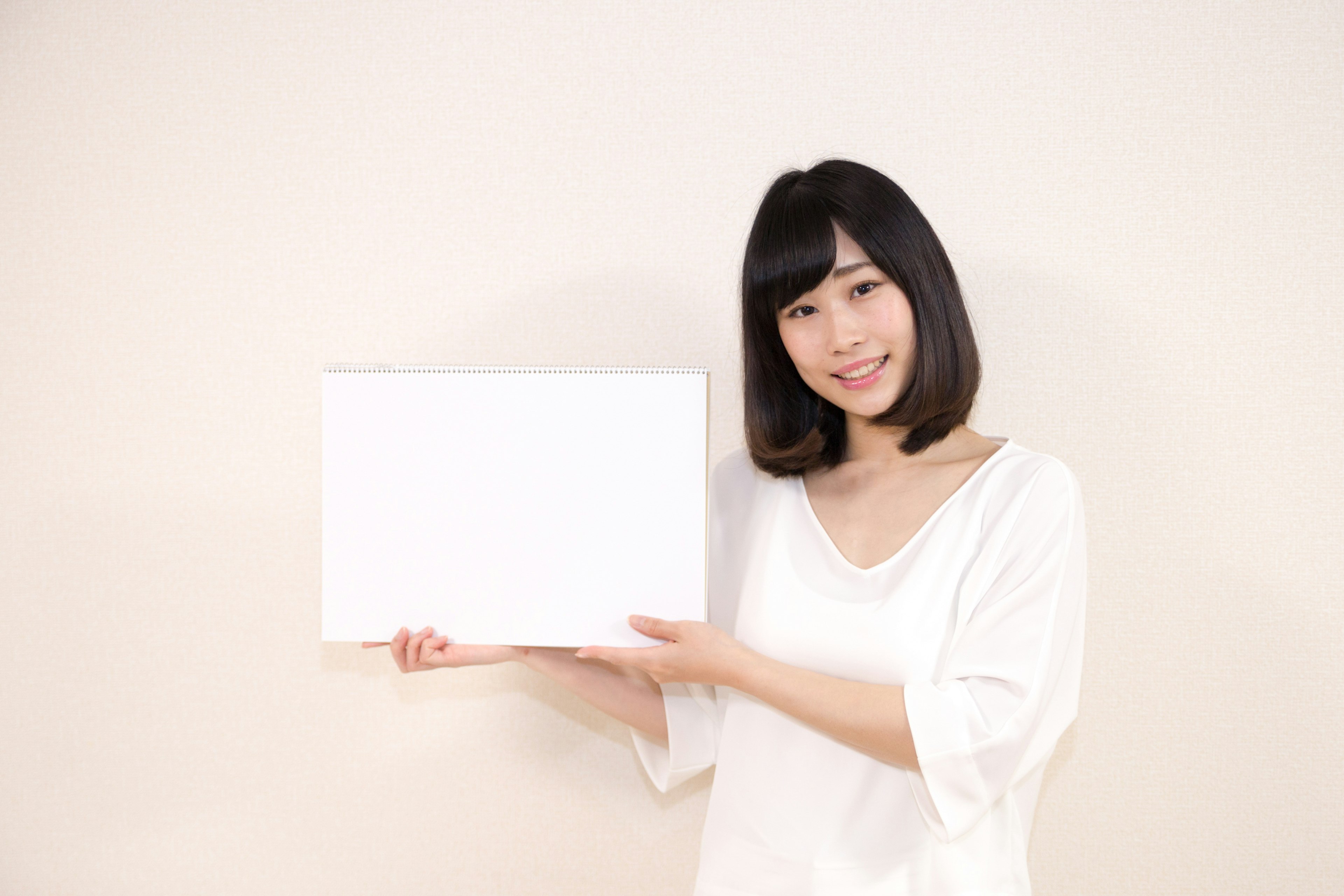 Une femme souriante tenant un tableau blanc vide