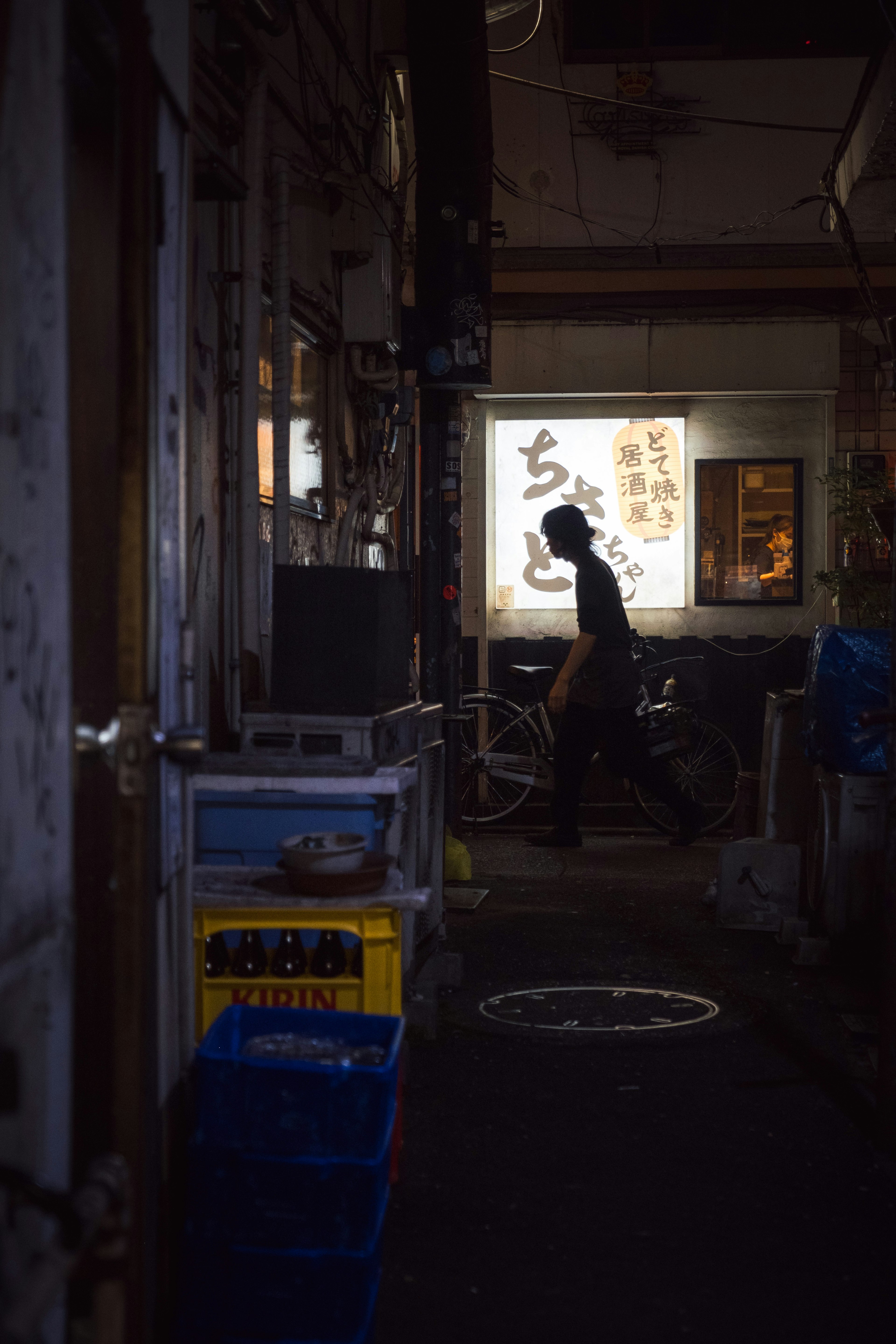 Silhouette d'une personne dans une ruelle sombre avec un éclairage de panneau