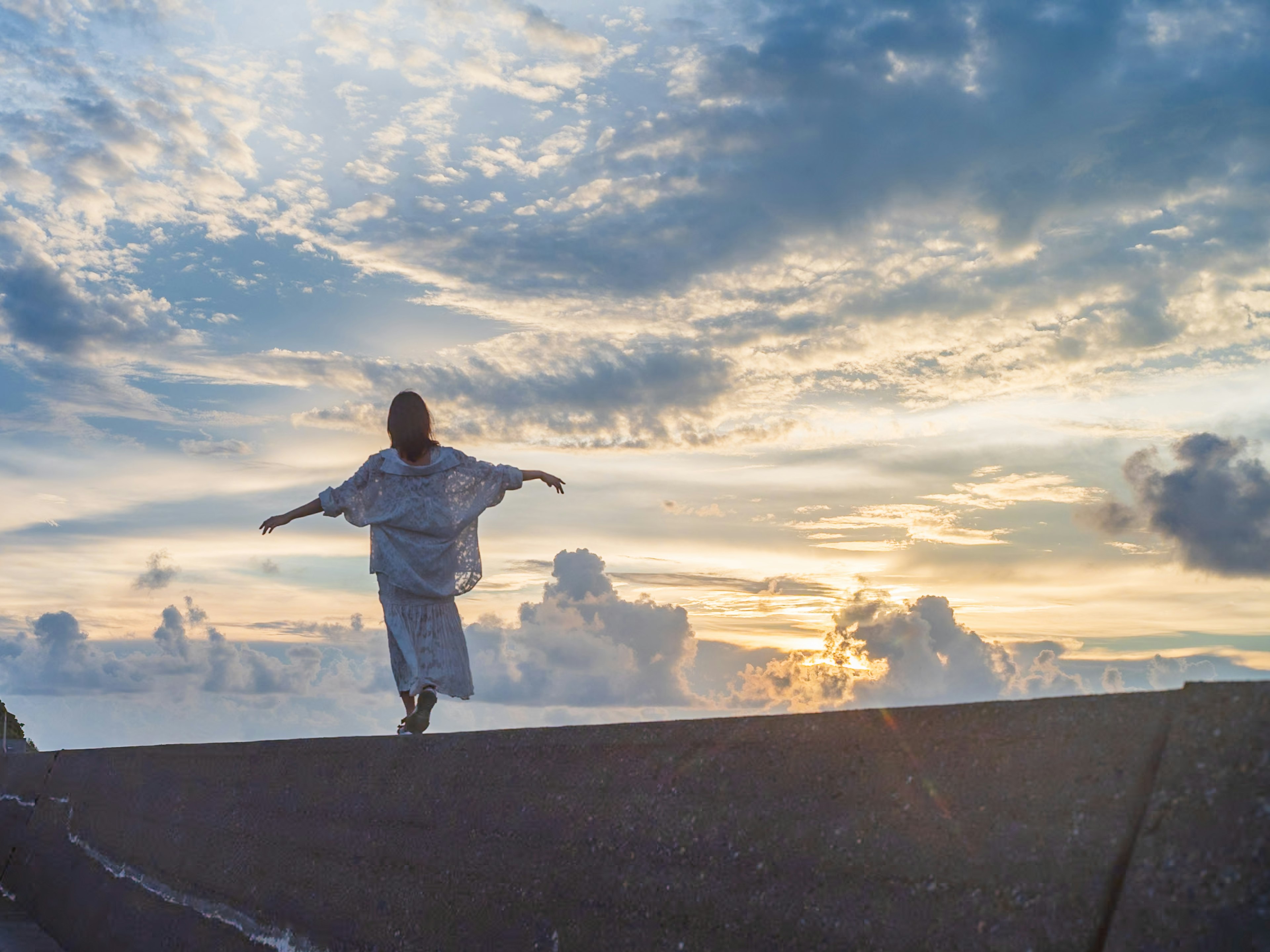 夕暮れ時に空を背景にして舞う女性のシルエット