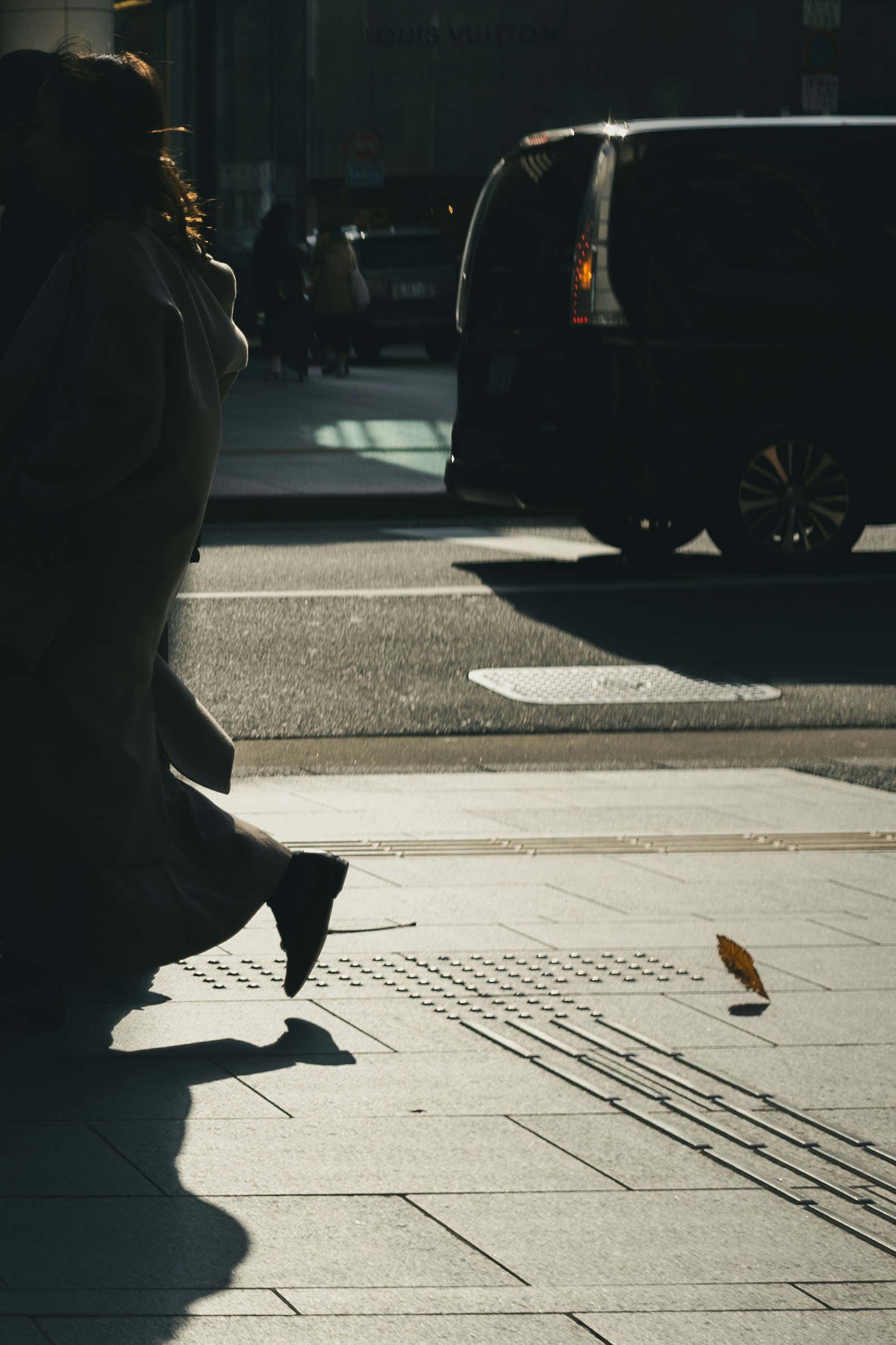 Silhouette d'une personne marchant dans la rue avec une feuille tombante