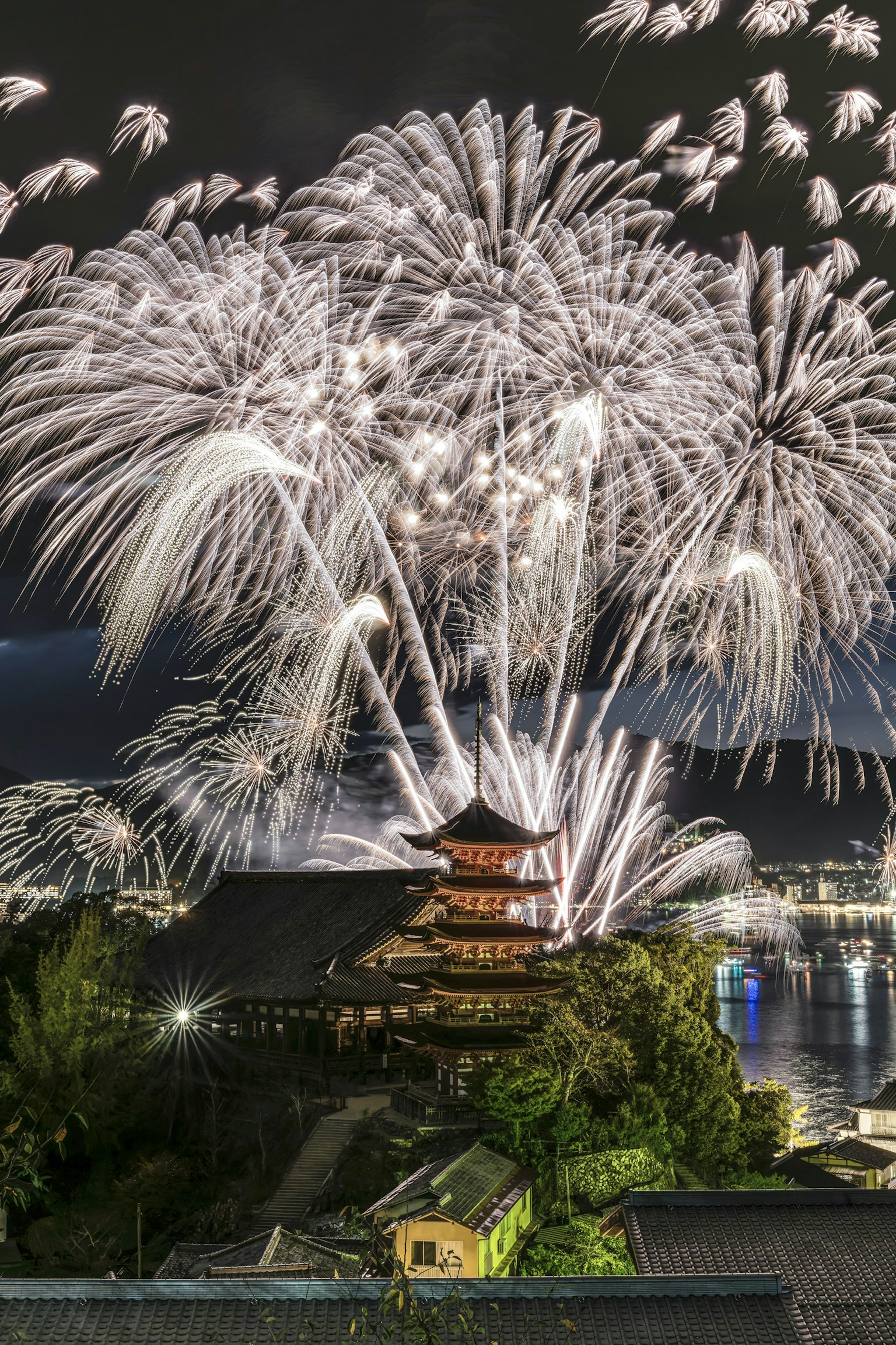 Fuochi d'artificio che illuminano il cielo notturno sopra un castello giapponese tradizionale