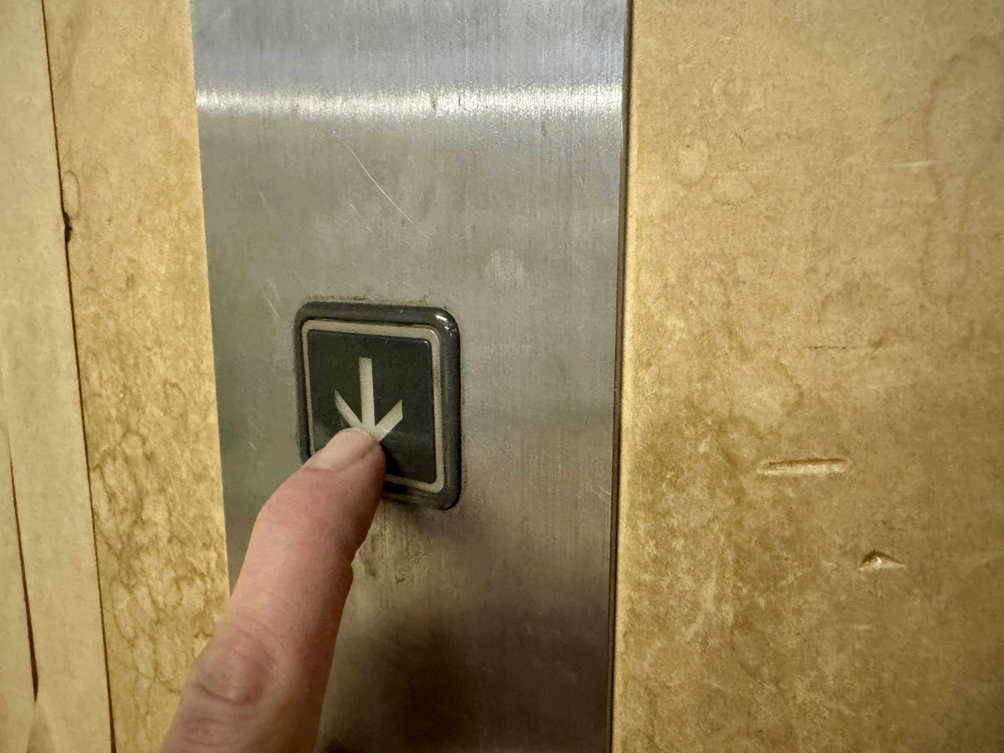 Jari menekan tombol lift di panel logam