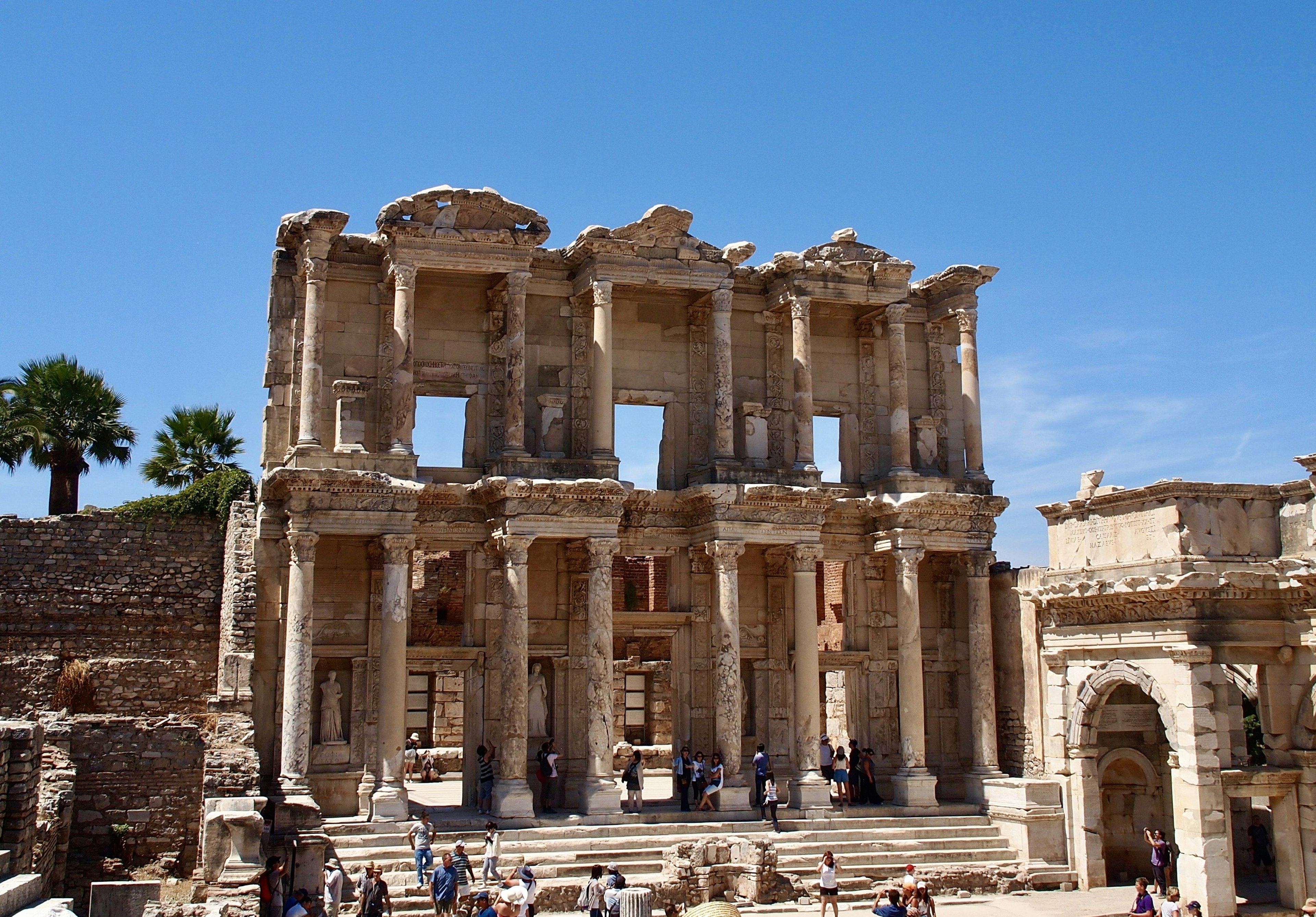 Ruinen der Celsus-Bibliothek in Ephesus mit Touristen unter einem klaren blauen Himmel