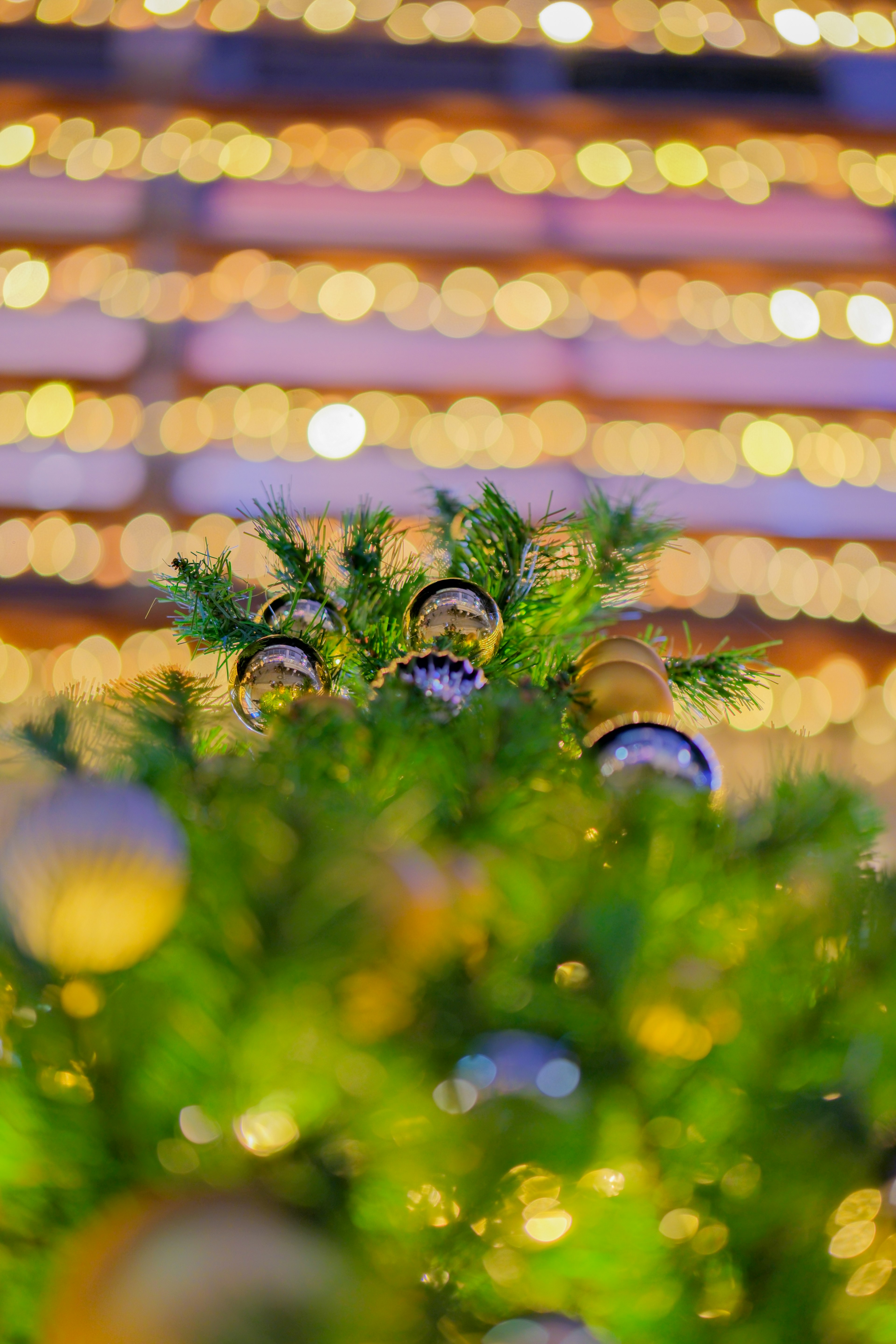 Gros plan sur le sommet d'un sapin de Noël orné d'ornements et de lumières scintillantes floues en arrière-plan