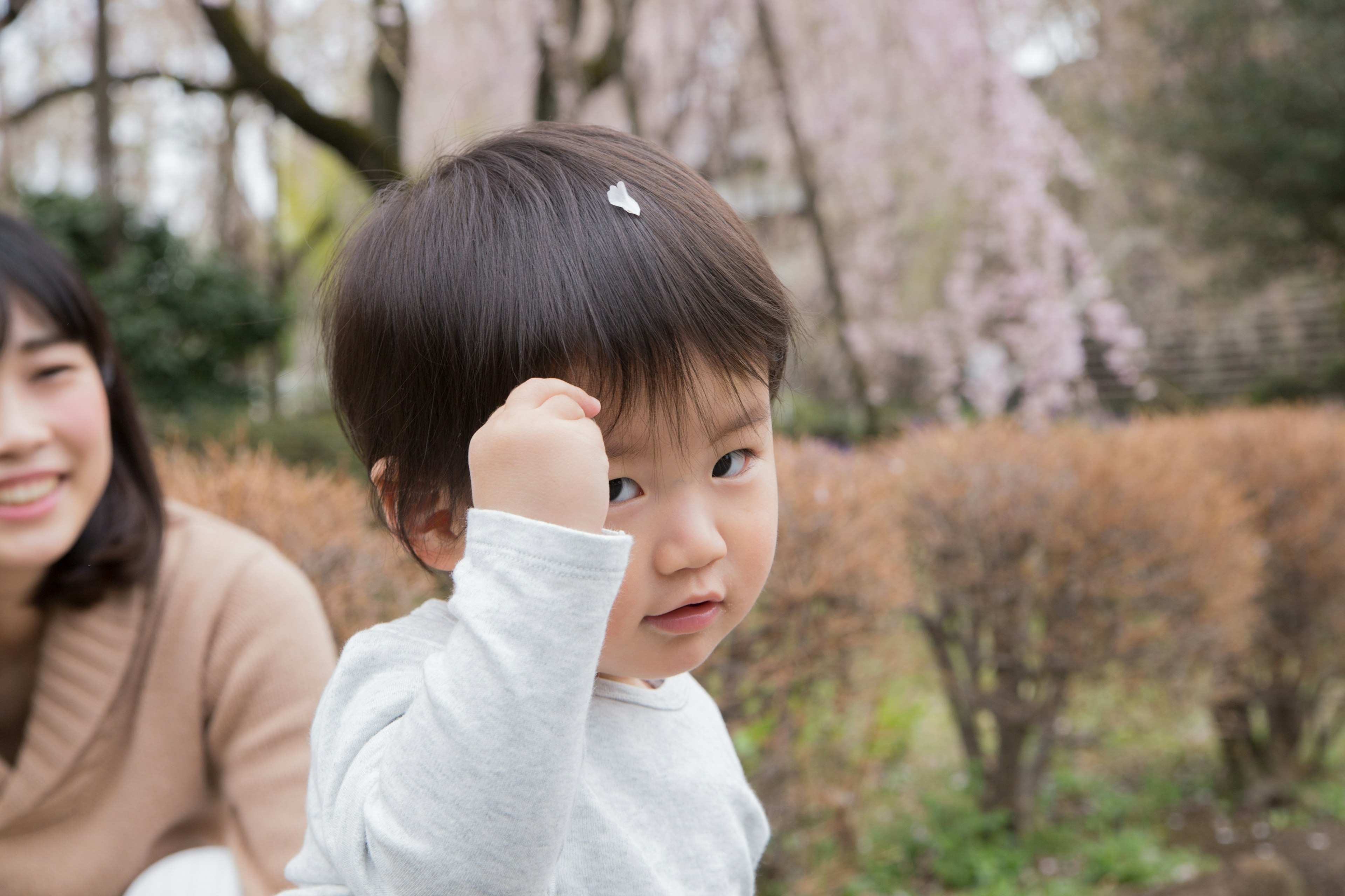 Child playing in a park with a smiling mother in the background