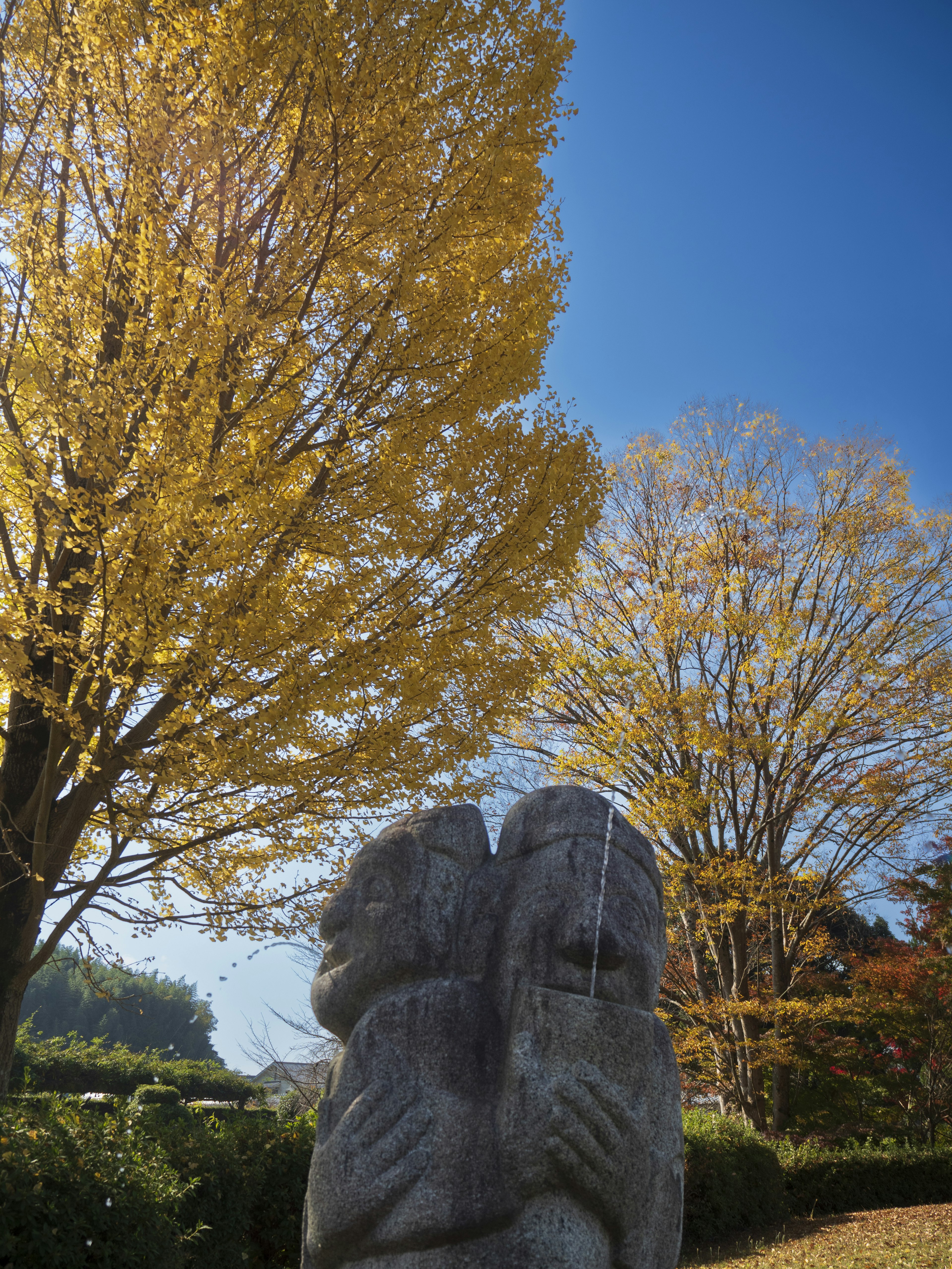 Statue en pierre de deux figures s'embrassant avec des feuilles jaunes d'automne