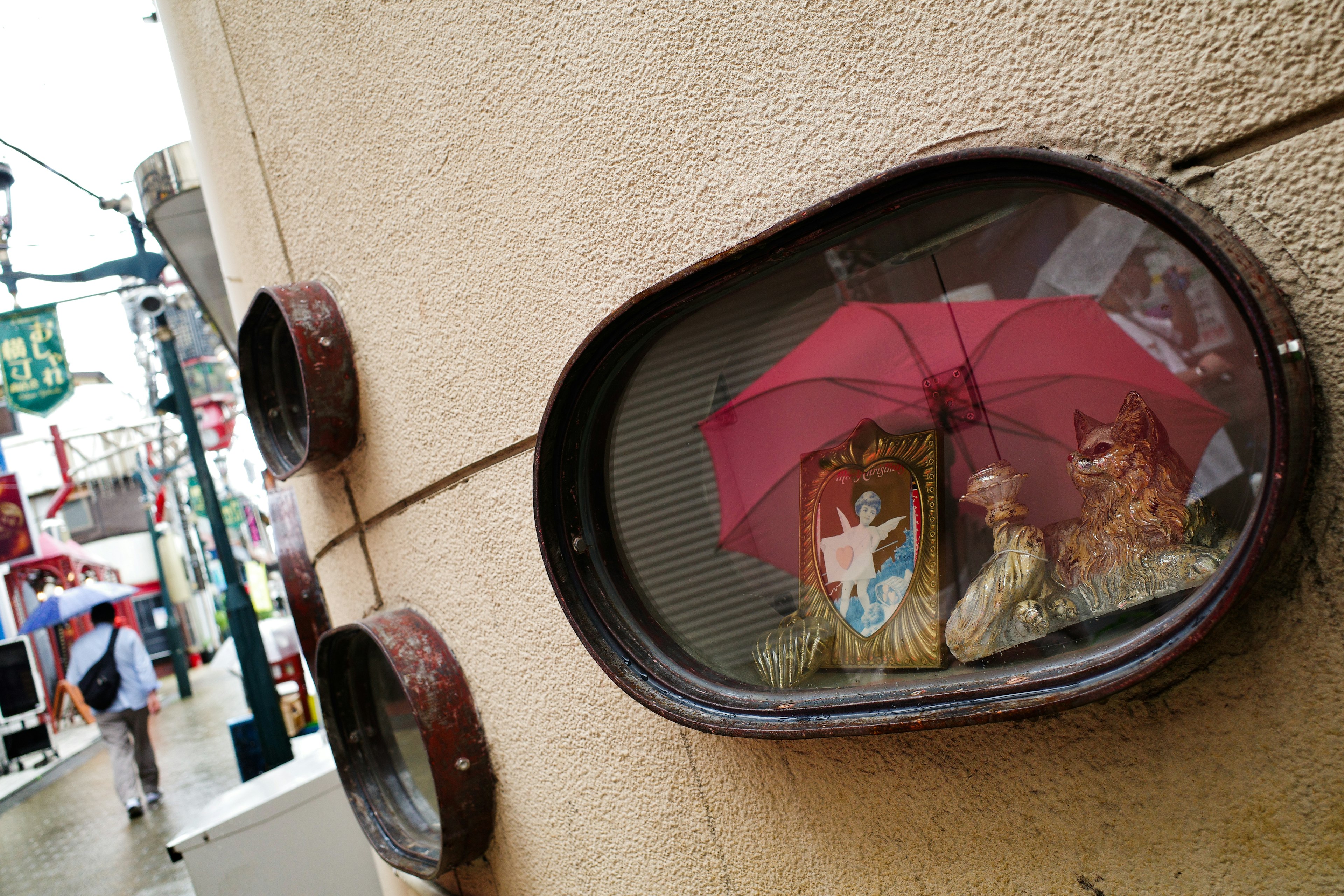 Display of a lion and chicken under a red umbrella in a shop window