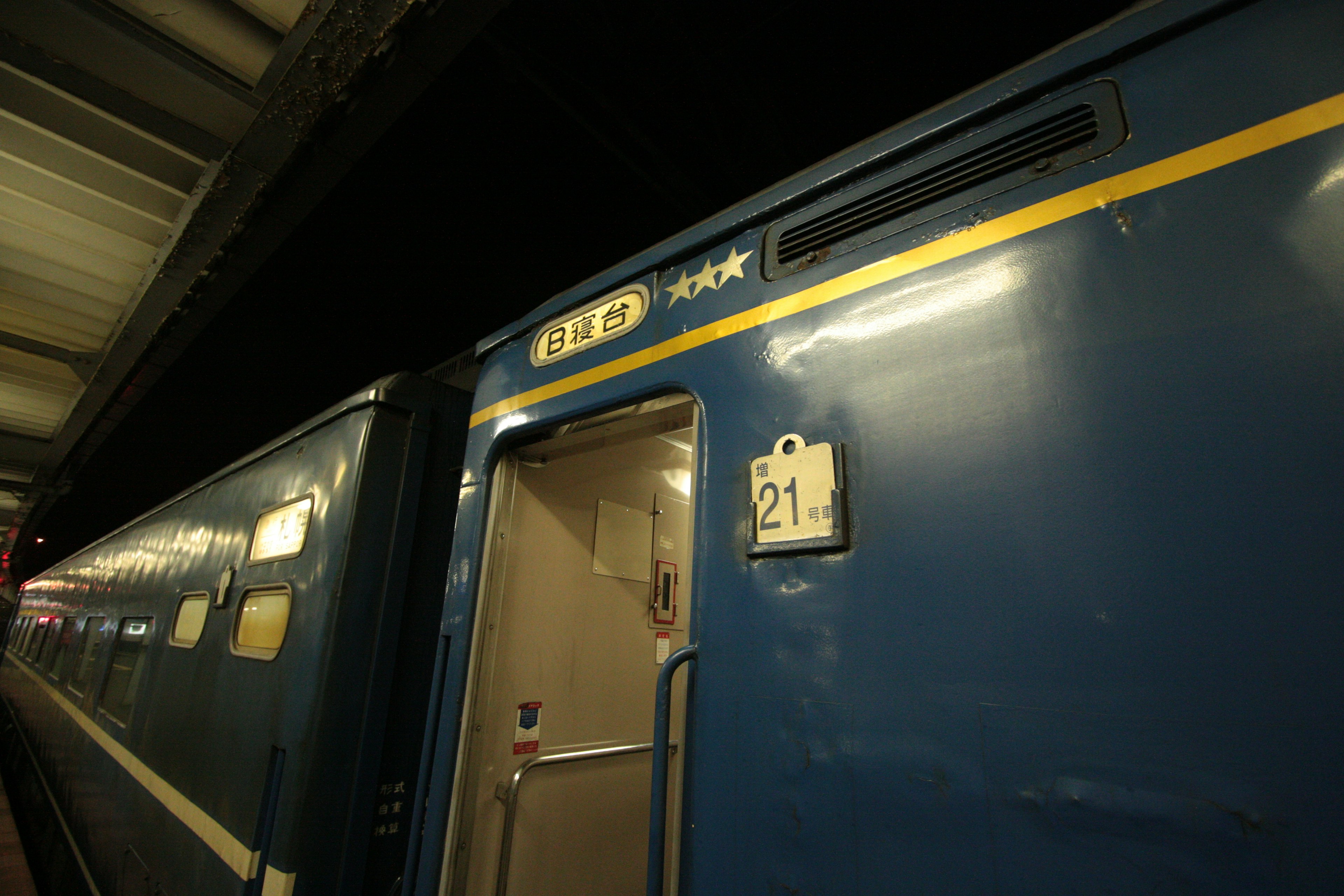 Blaue Zugtür mit sichtbarer Wagennummer 21 an einem Bahnhof