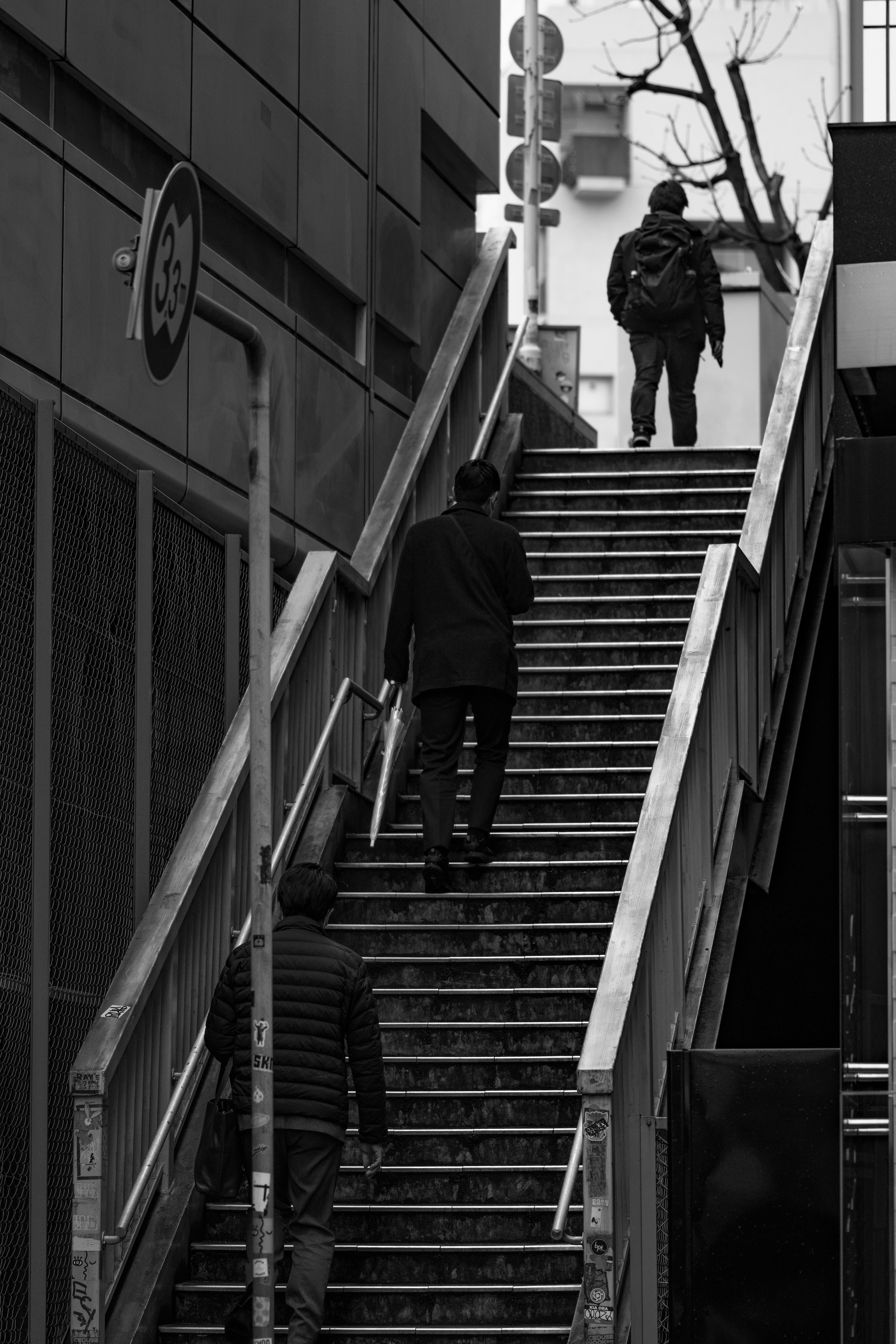 Des personnes montant des escaliers dans un cadre urbain en monochrome