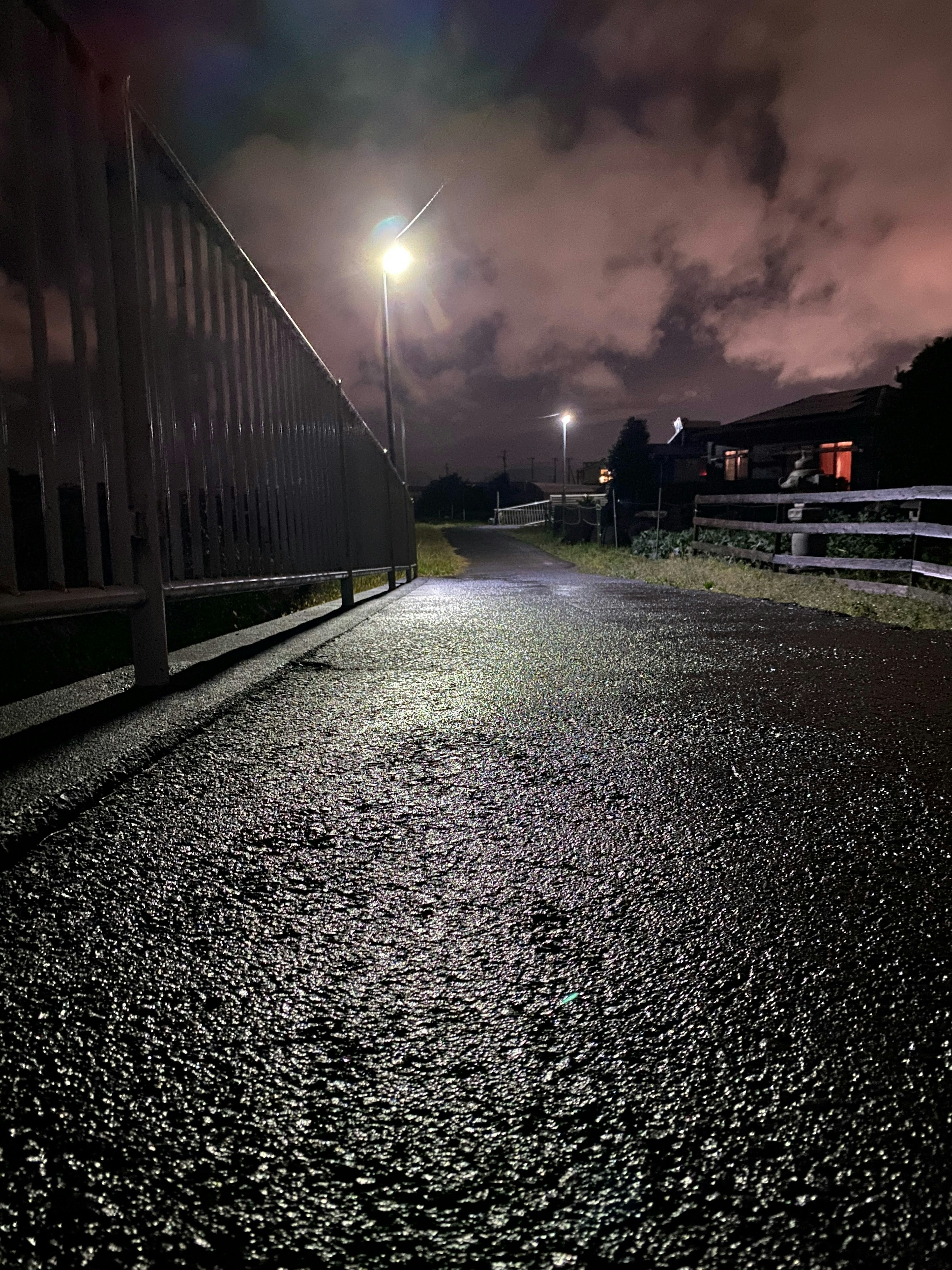 Pflasterweg und Straßenlaternen von unten unter einer Brücke bei Nacht gesehen