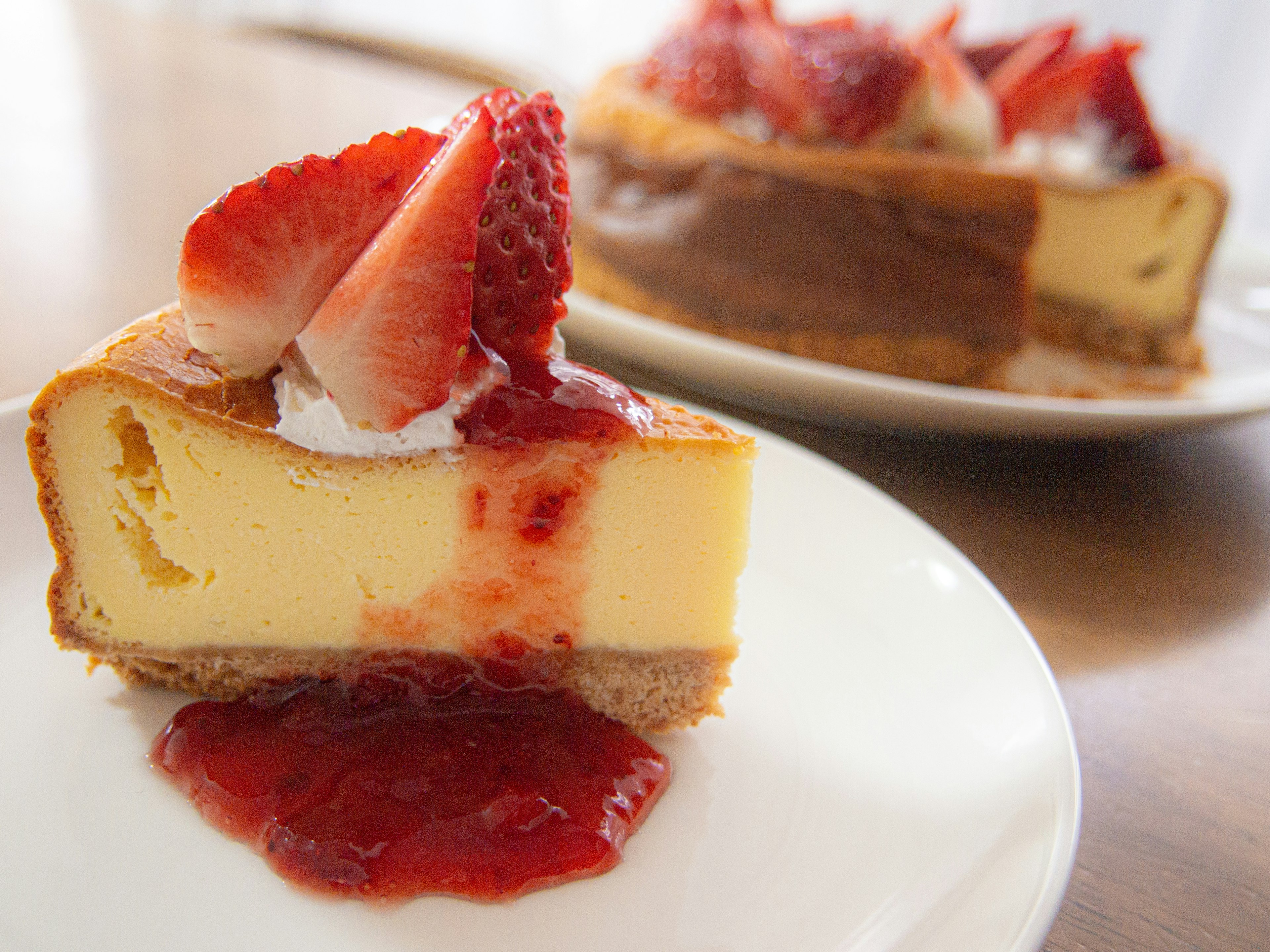 Cross-section of cheesecake topped with strawberry sauce and fresh strawberries