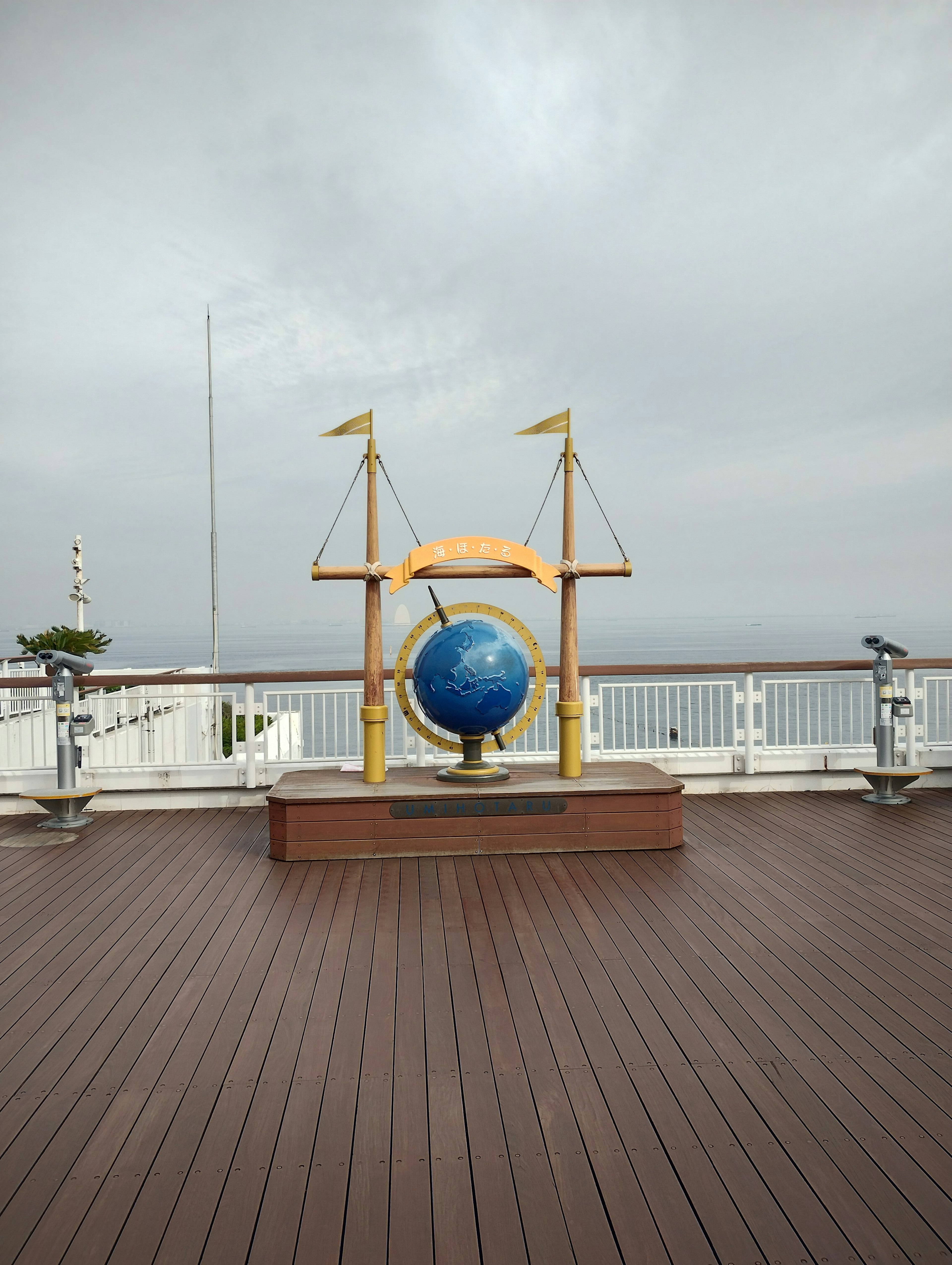 Decorative globe with blue earth on a ship deck under cloudy sky