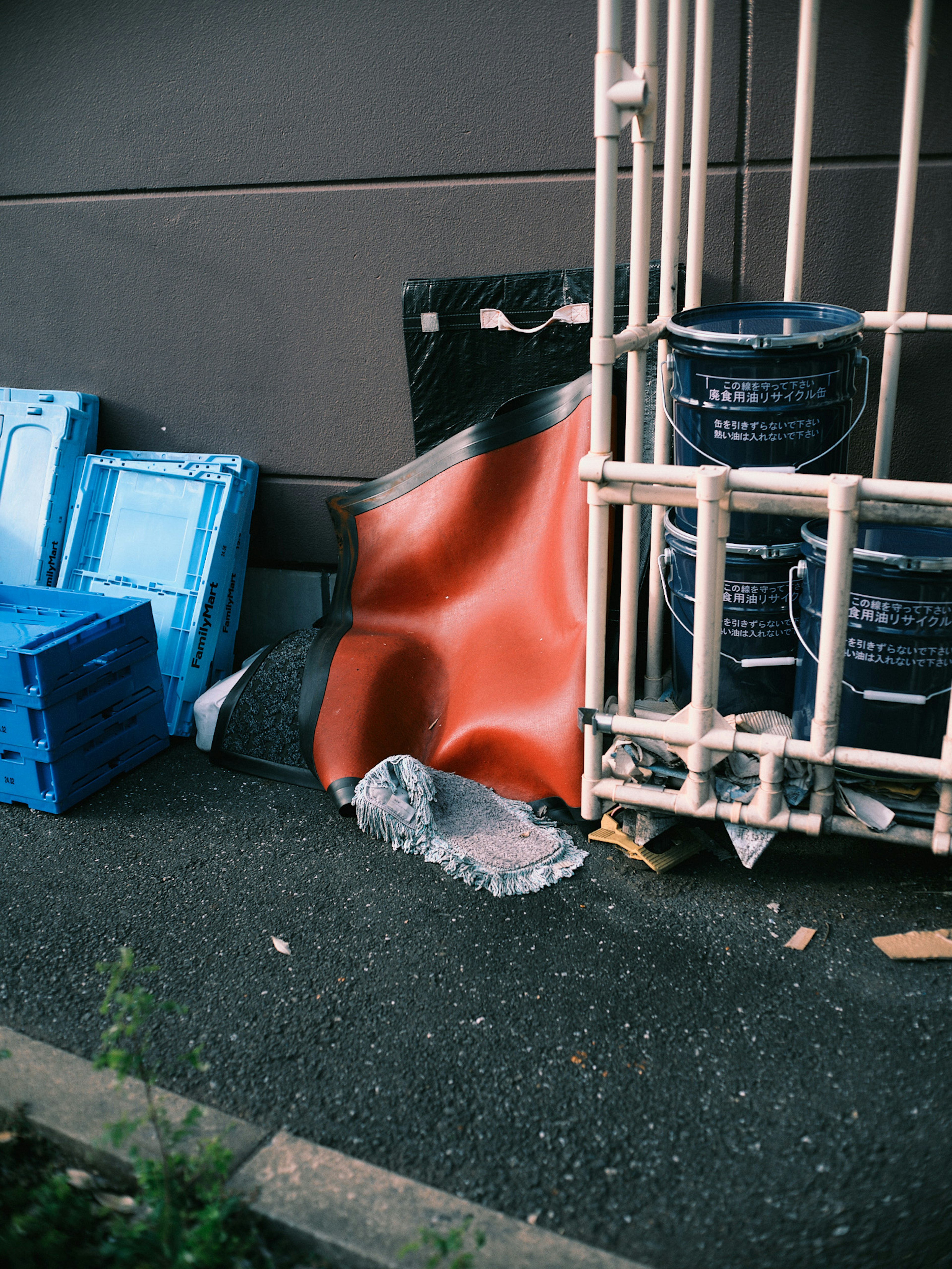 Area with blue plastic crates and a red sheet near waste