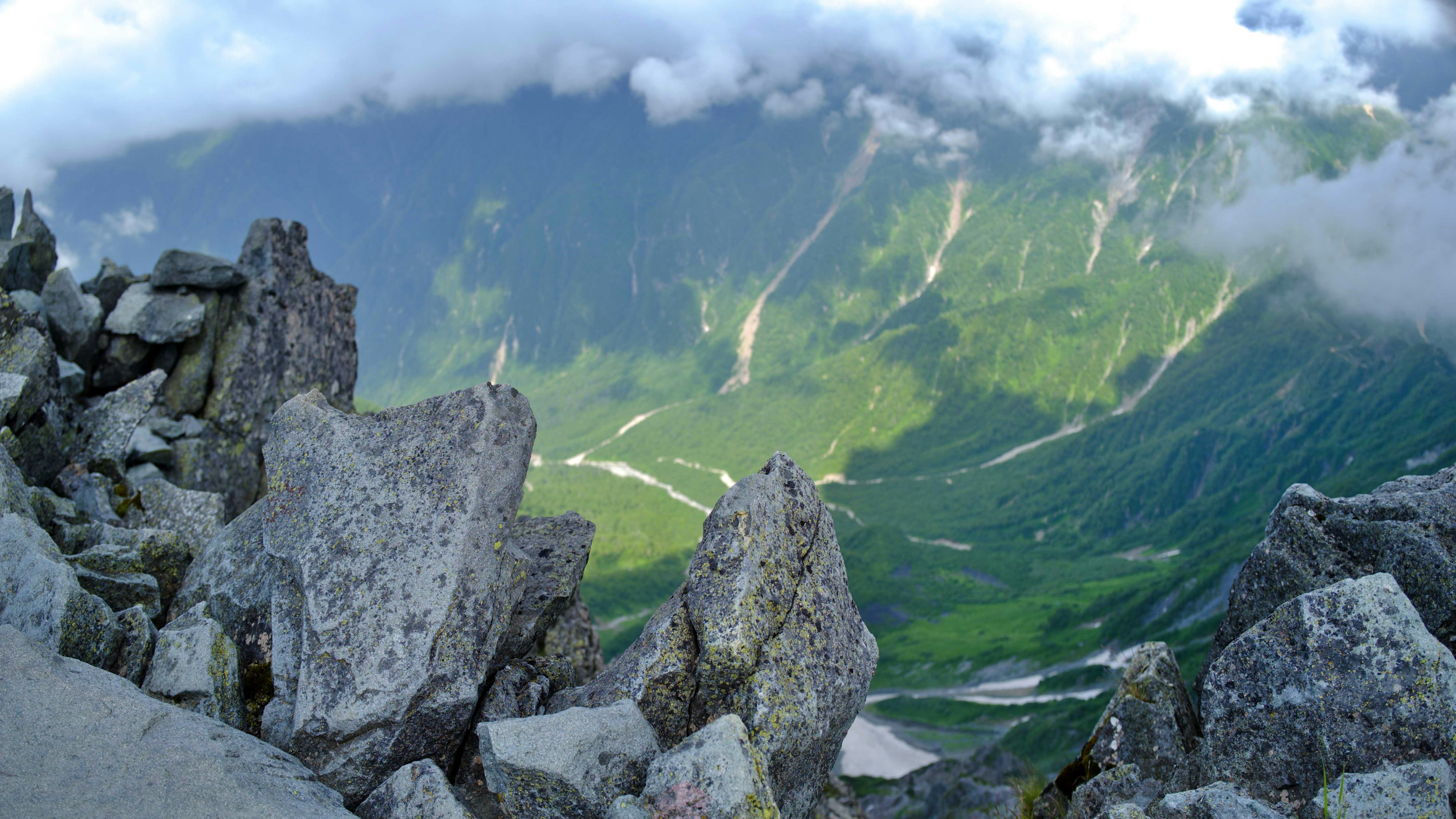 Vista dalla cima della montagna che sovrasta una valle verde e nuvole