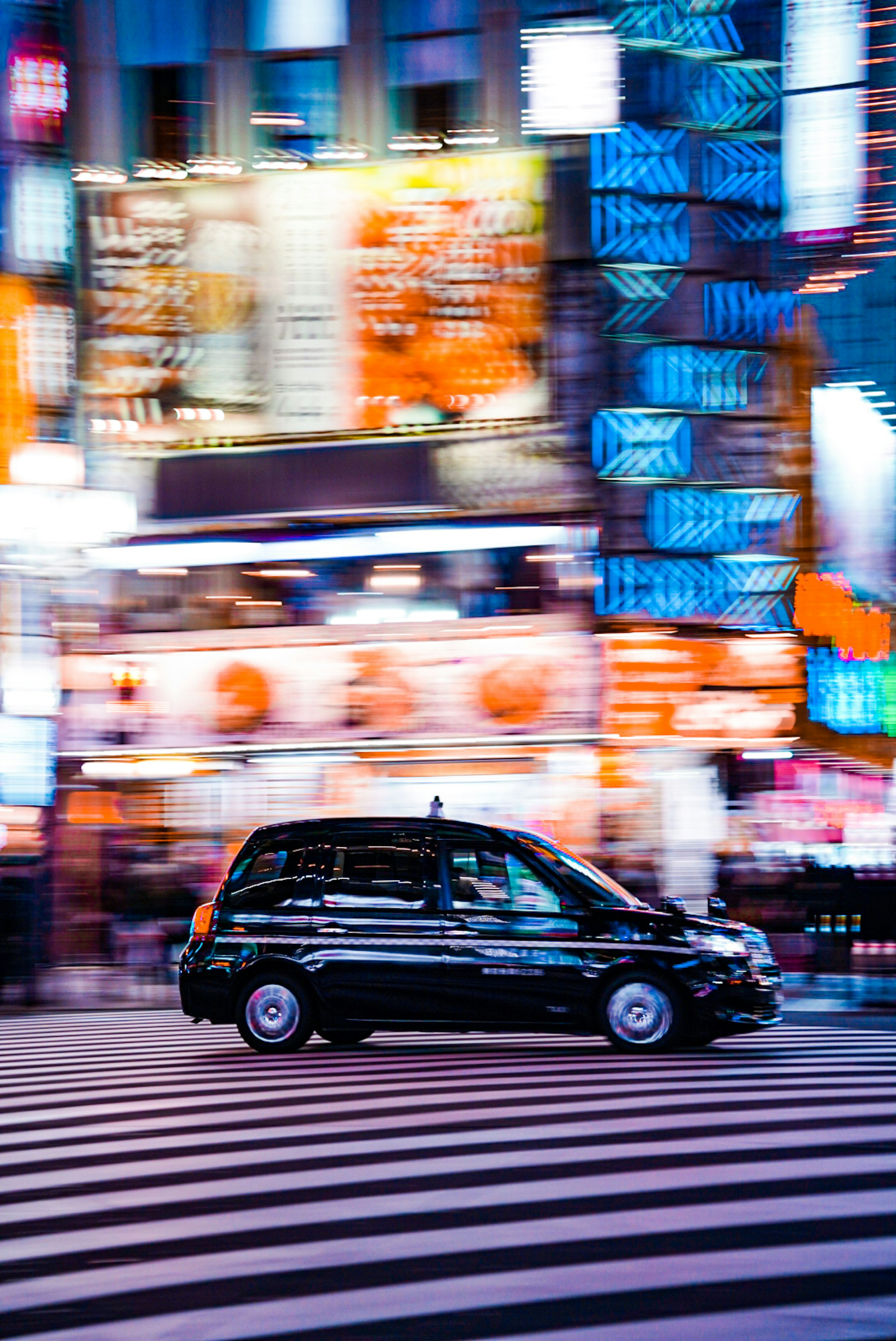 Taxi in motion on a city street with colorful neon signs at night