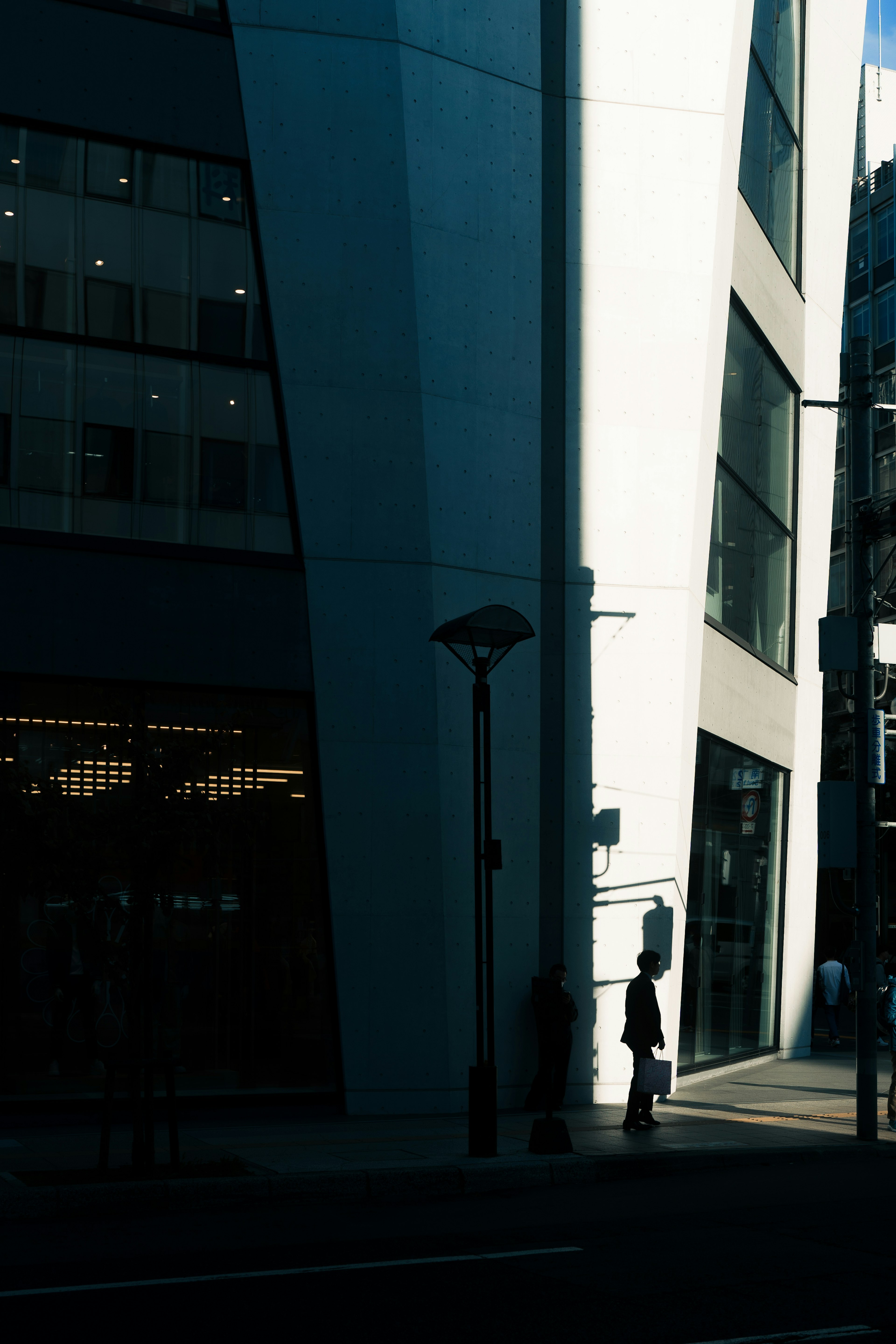 Urban scene featuring a shadowed building corner and a silhouetted figure