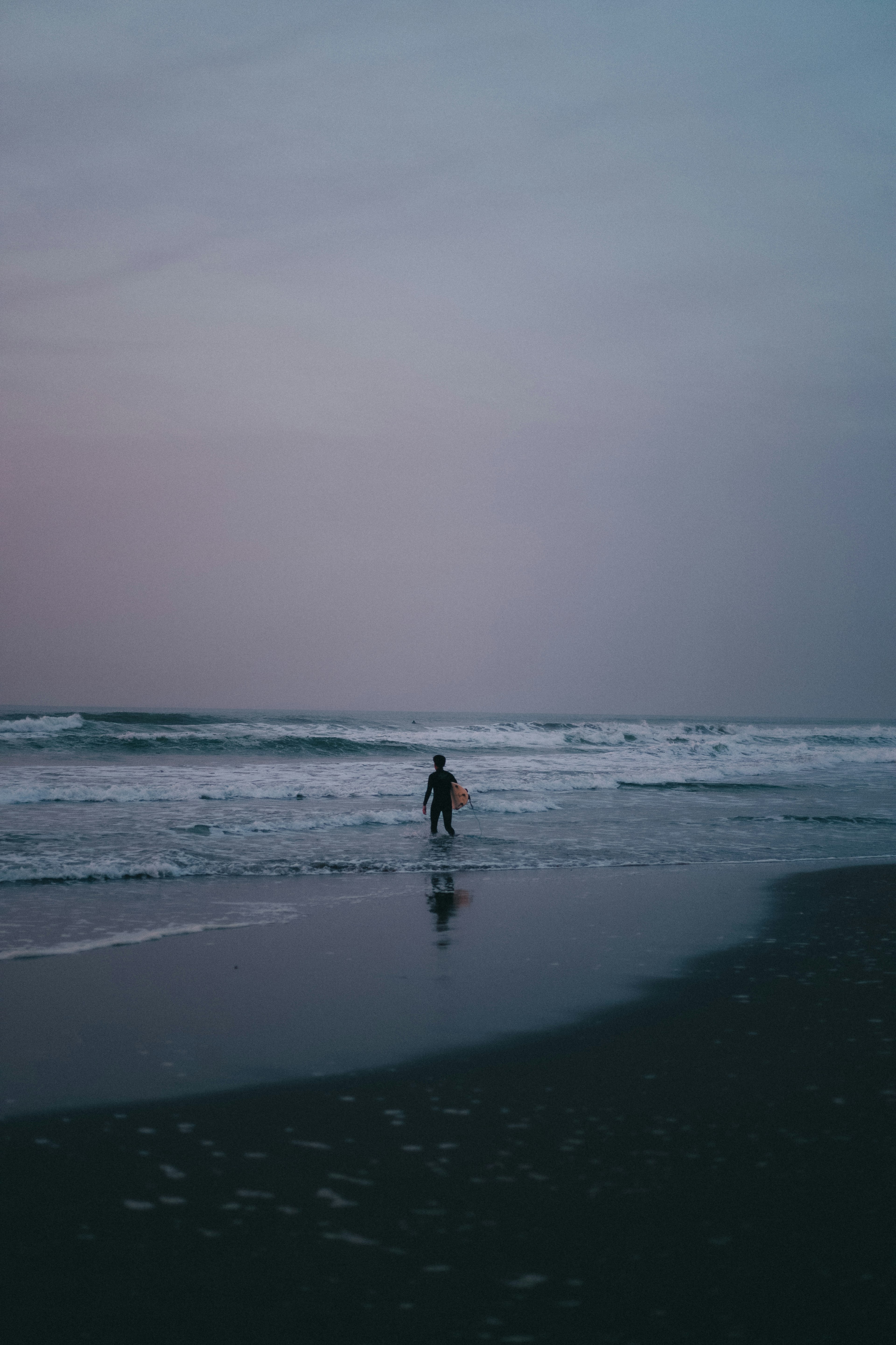 Silhouette di una persona con una tavola da surf sulla spiaggia