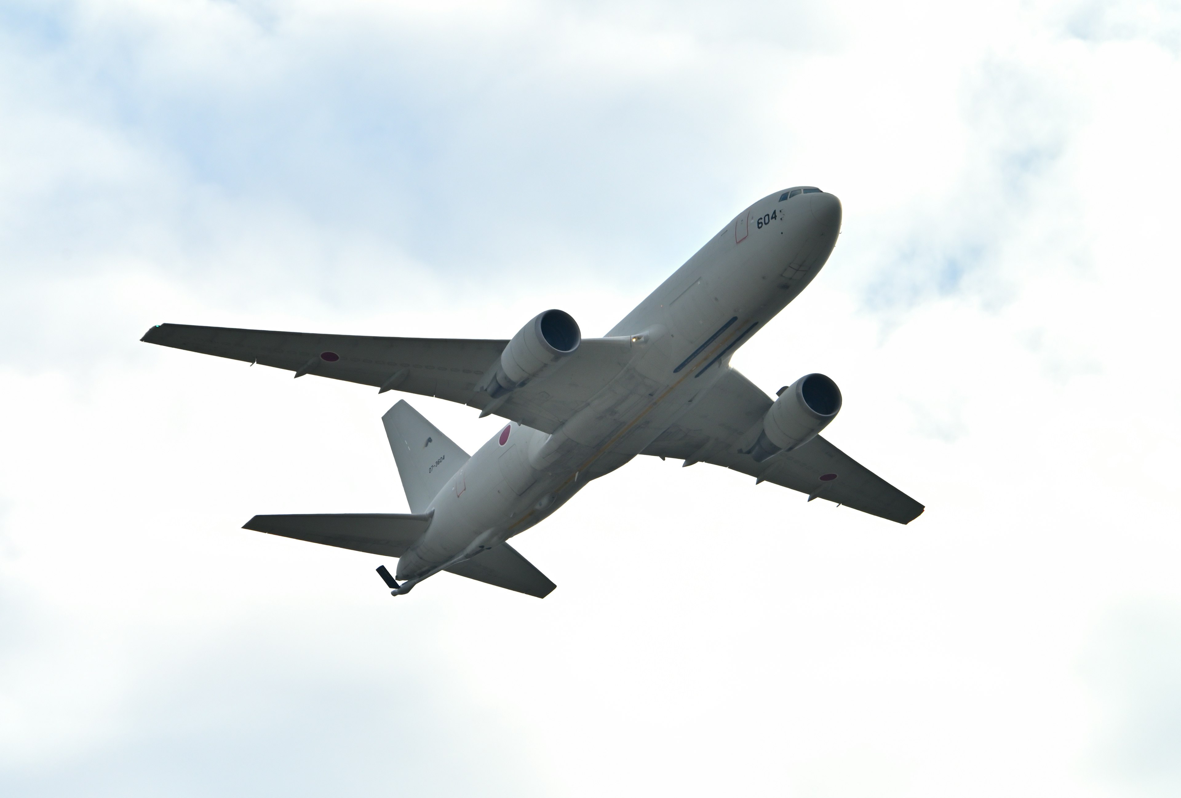 Passenger airplane flying against a cloudy sky from a below perspective