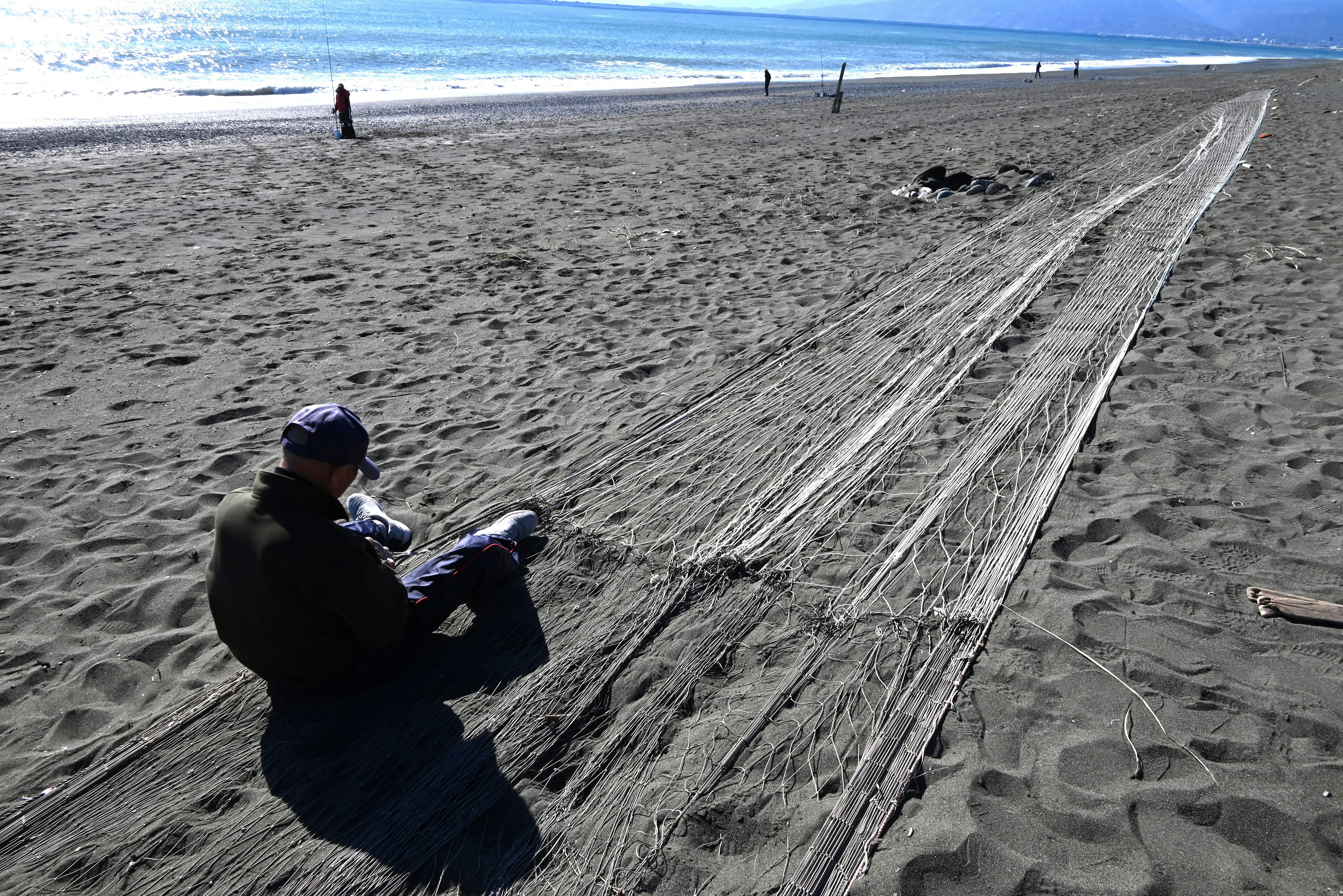 Fischer, der Fischernetze am Strand ordnet