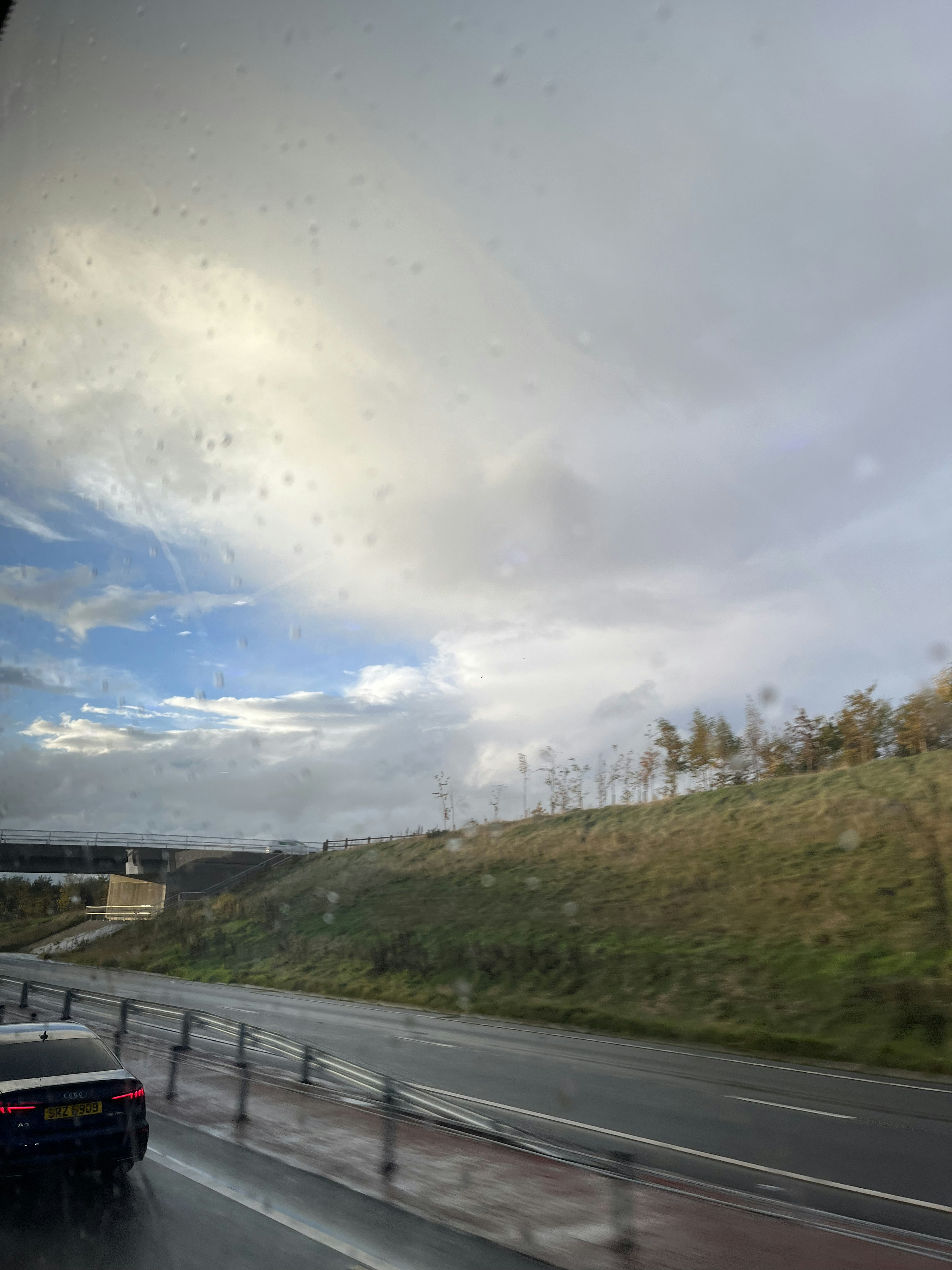 從車窗外的景色 顯示雨天的風景 藍天和雲 綠色山丘和道路