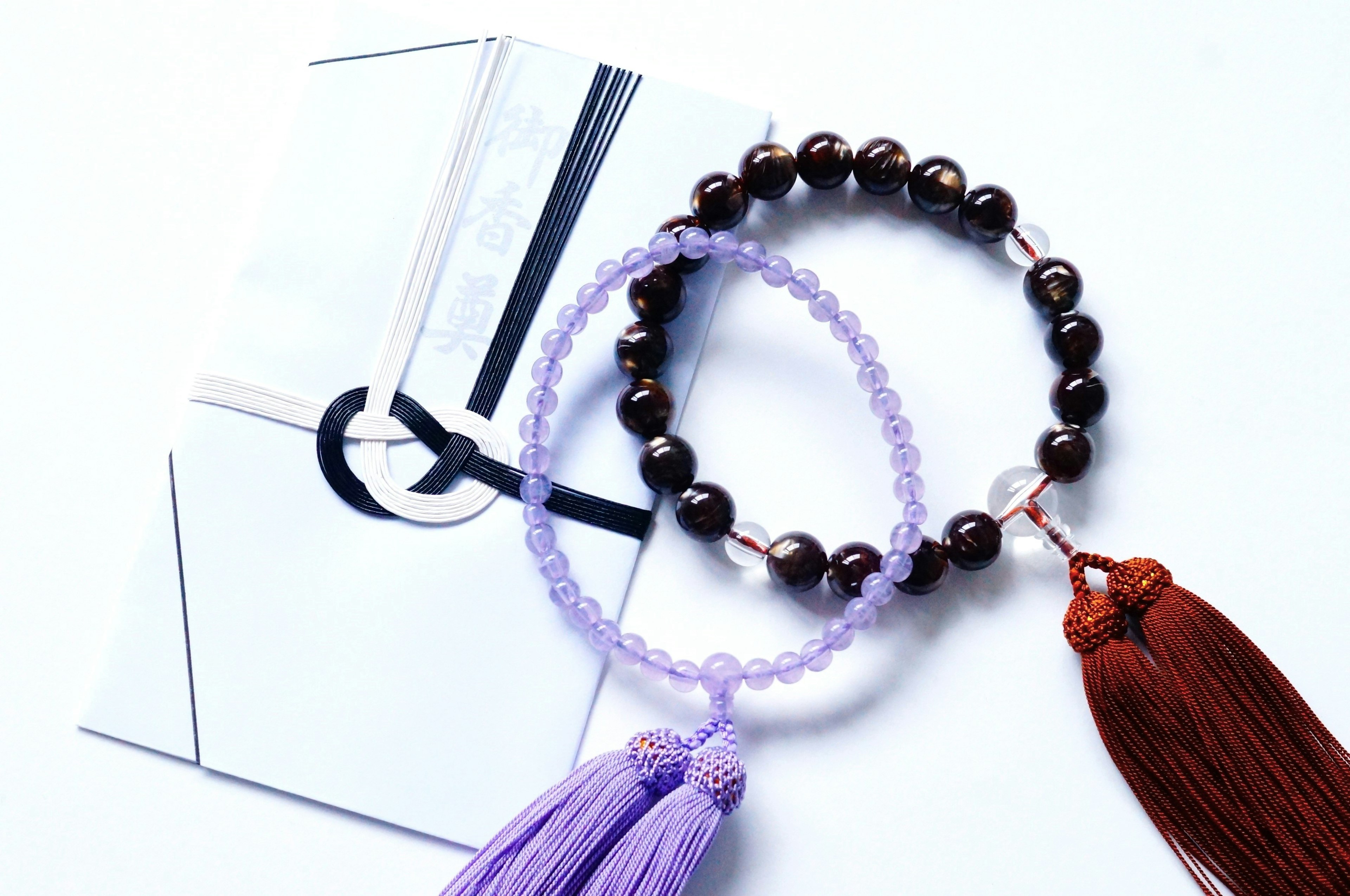 Bracelets en perles noires et violettes avec des glands à côté d'une enveloppe blanche