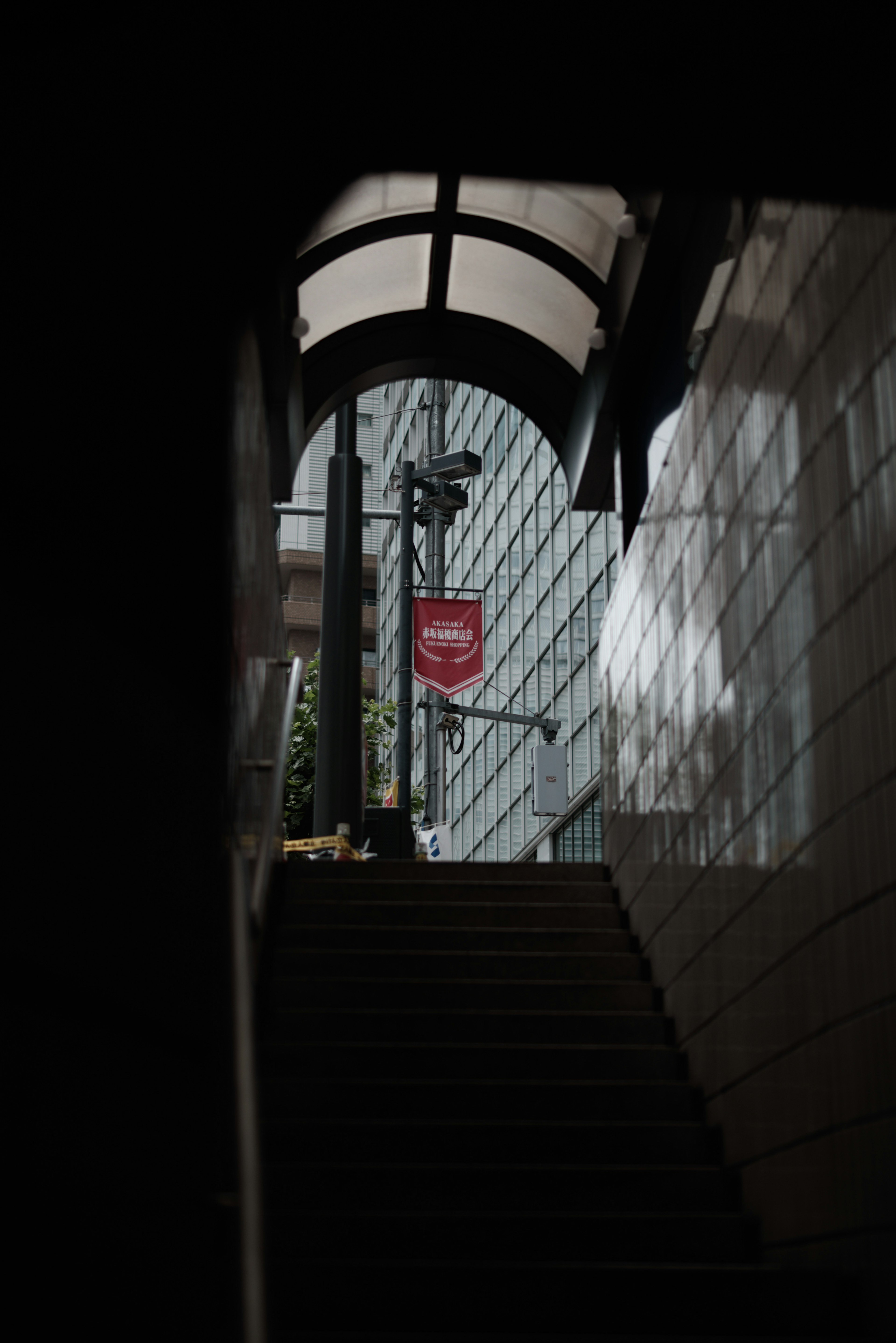 Couloir sombre avec un toit en arc menant à des escaliers et un panneau rouge