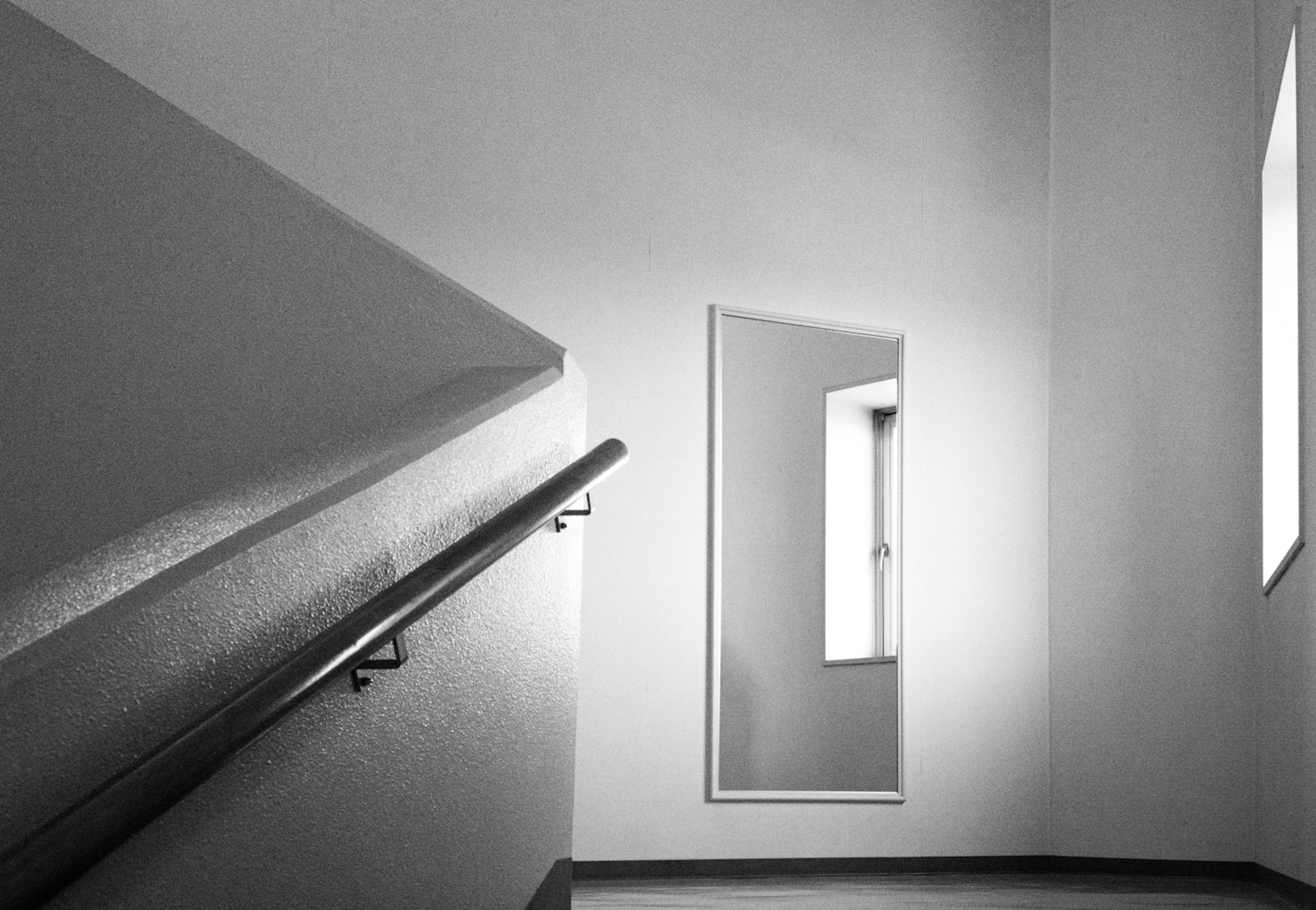 Salle avec un garde-corps d'escalier et un miroir sur un mur blanc