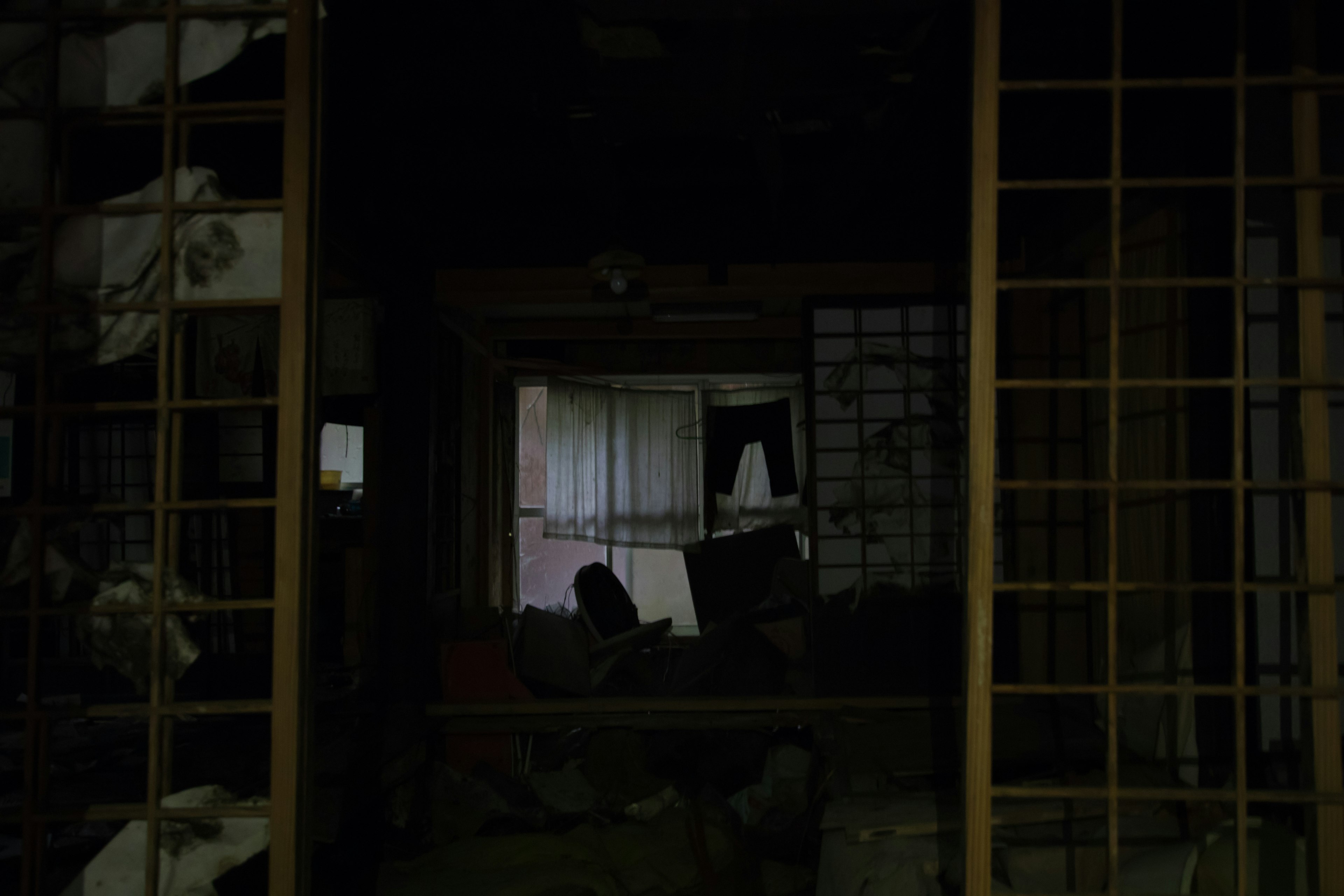 Dimly lit corridor leading to a dilapidated room with old sliding doors