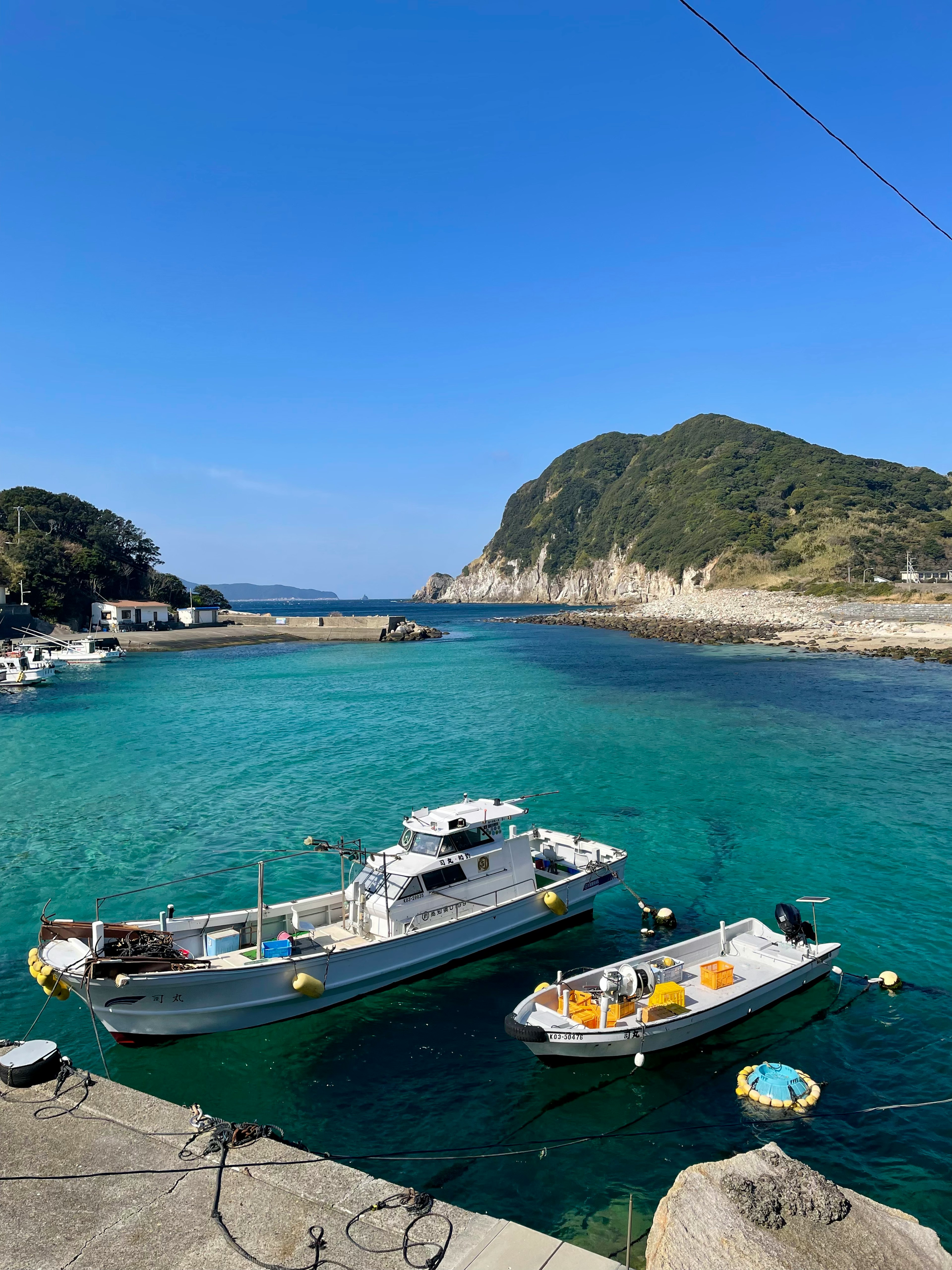 青い海に浮かぶ漁船と美しい山の風景