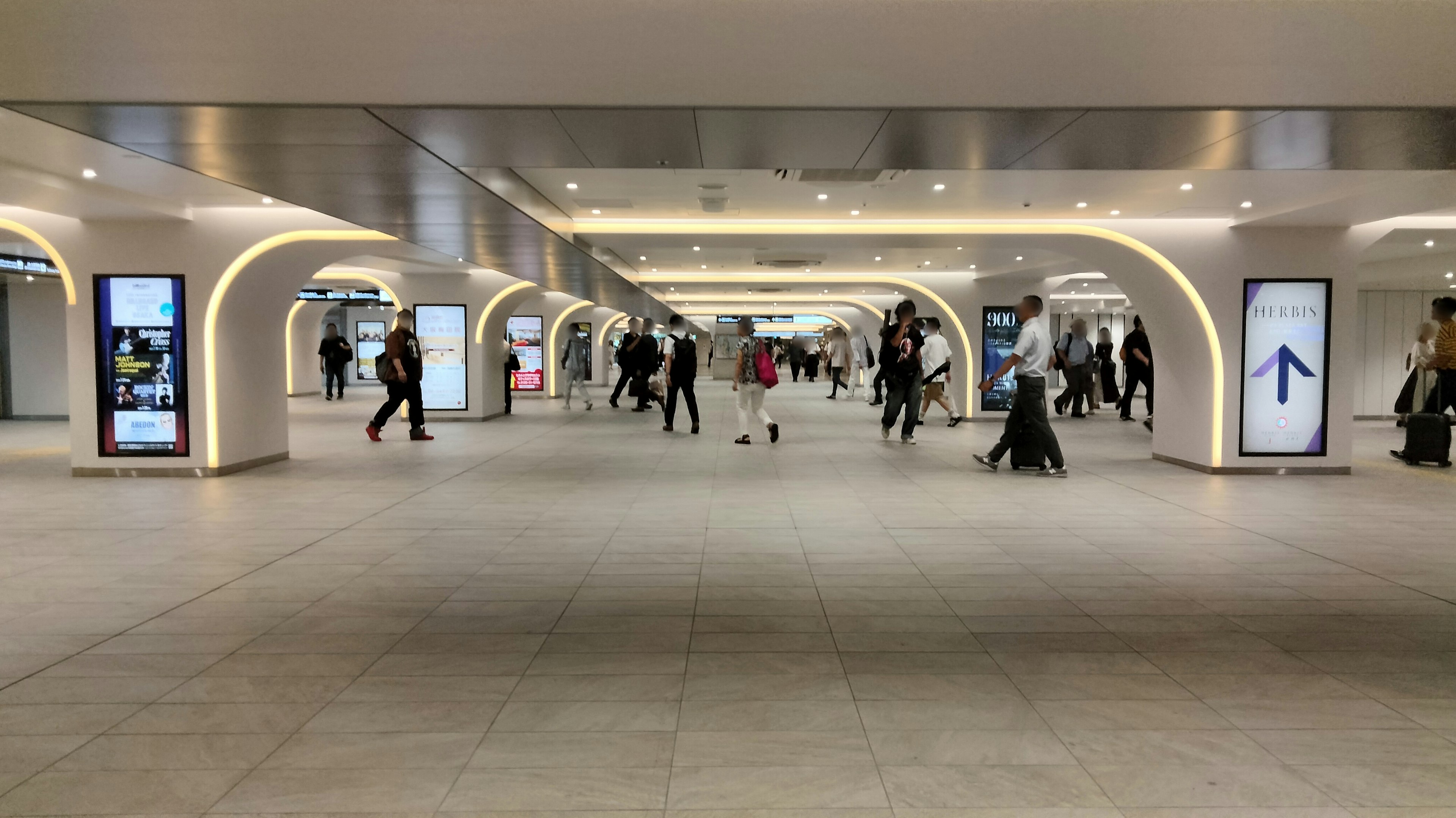 Amplio corredor subterráneo con personas caminando y una iluminación brillante